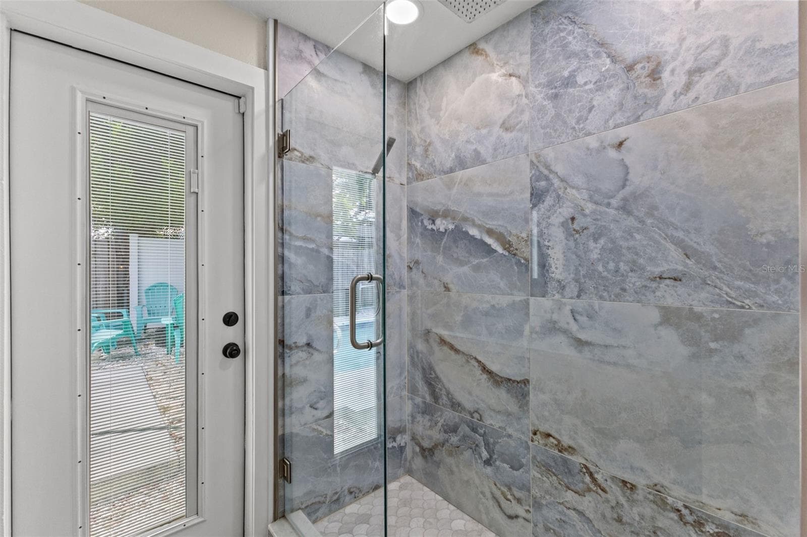 Beautifully tiled walk-in shower with frameless glass enclosure, oversized tile, and a rainfall-style showerhead. - 201 SOUTH ST, PALM HARBOR