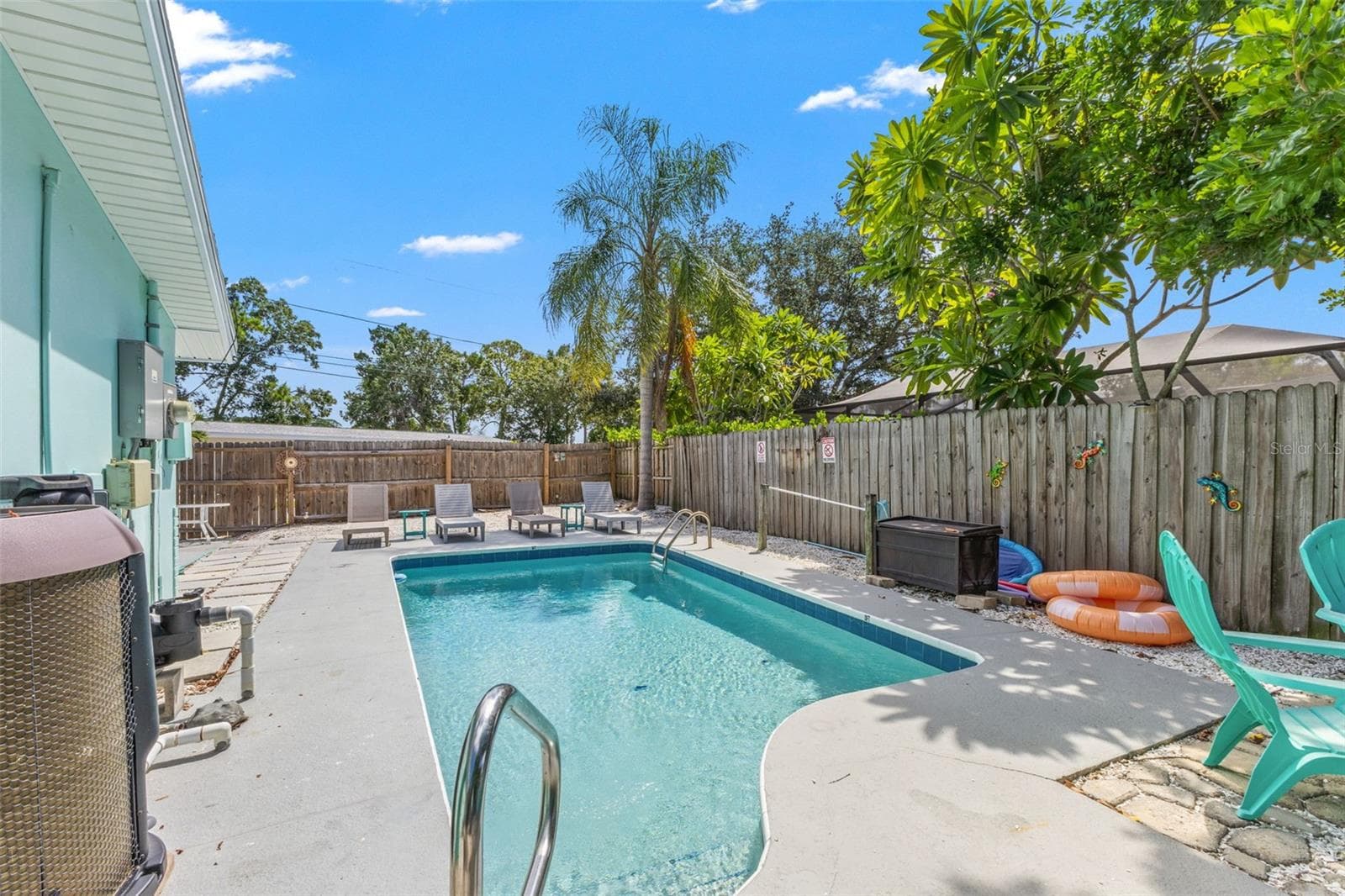 Private heated pool surrounded by multiple areas for lounging and outdoor entertaining, with a new pool pump and heater added in 2025. - 201 SOUTH ST, PALM HARBOR