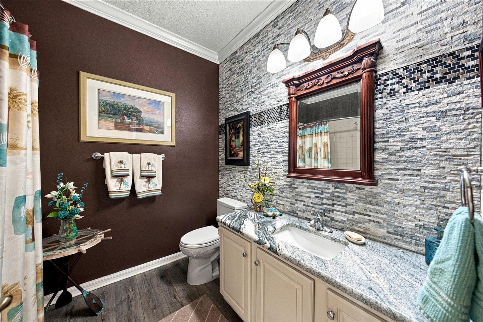 The recently remodeled guest bath has an elongated stool, stone counters, upgraded plumbing and lighting fixtures. The stone wall with accents adds to the richness of this space. - 4232 DORNOCH DR, LAKE WALES