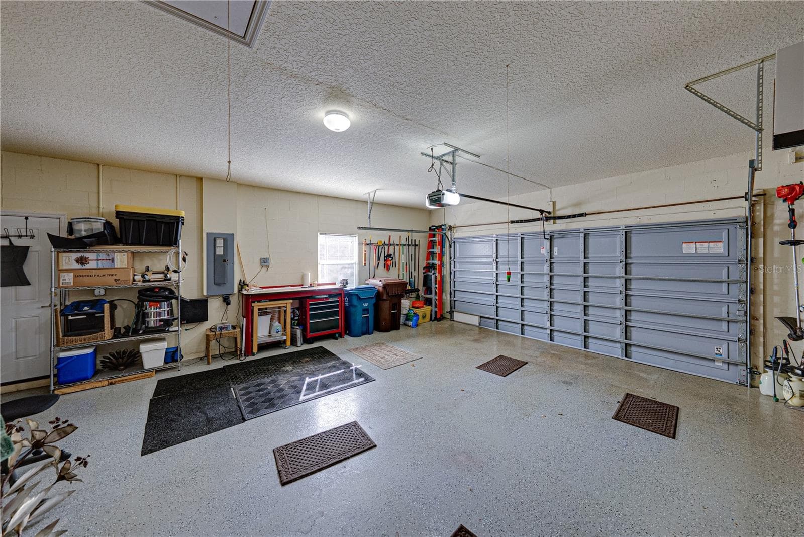 The attached 2 car garage has epoxy flooring, window, service door, and pull-down attic ladder. - 4232 DORNOCH DR, LAKE WALES
