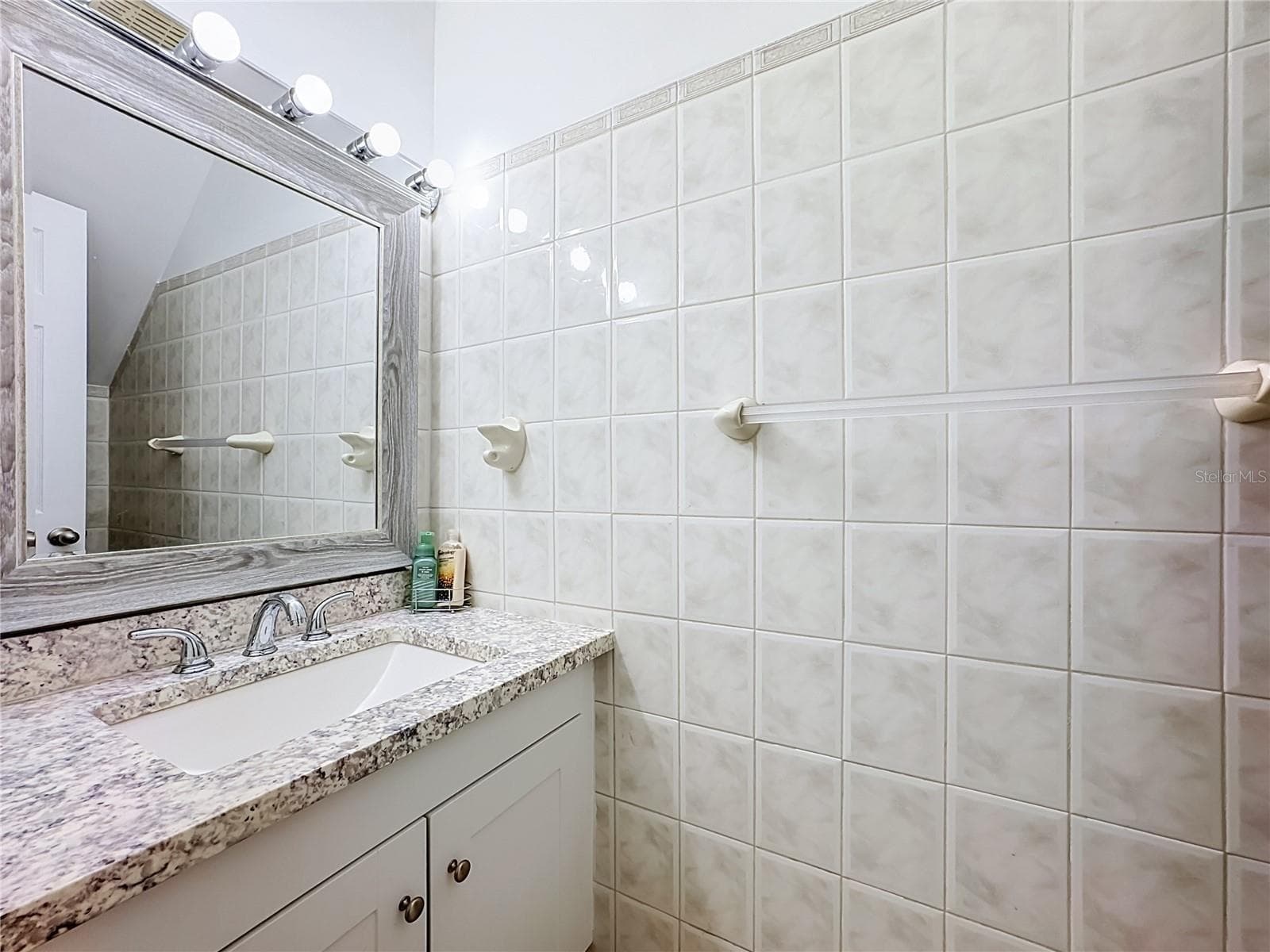 Bathroom vanity with tiled walls. - 1106 SPRING MEADOW DR, KISSIMMEE