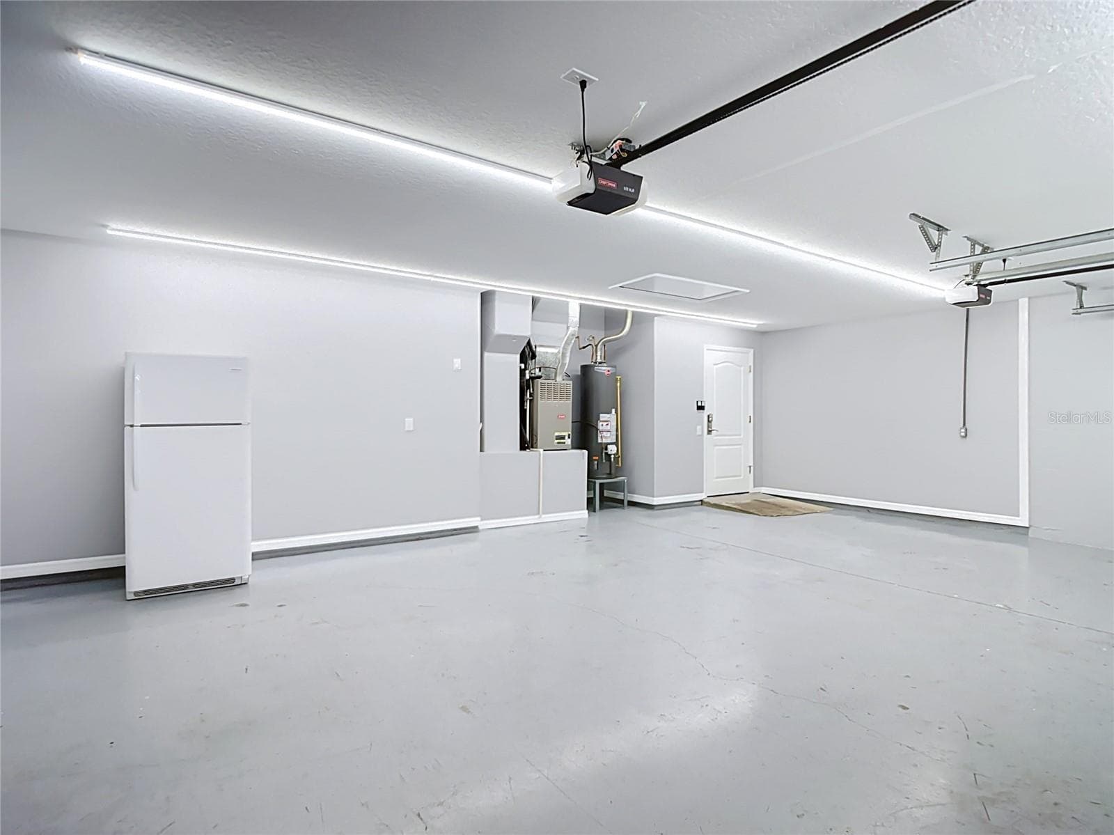 The impressive three-car garage offers exceptional versatility and functionality, featuring a dedicated electrical panel ideal for a workshop or electric vehicle charging, along with high-output LED shop lighting - 18316 CYPRESS HAVEN DR, TAMPA