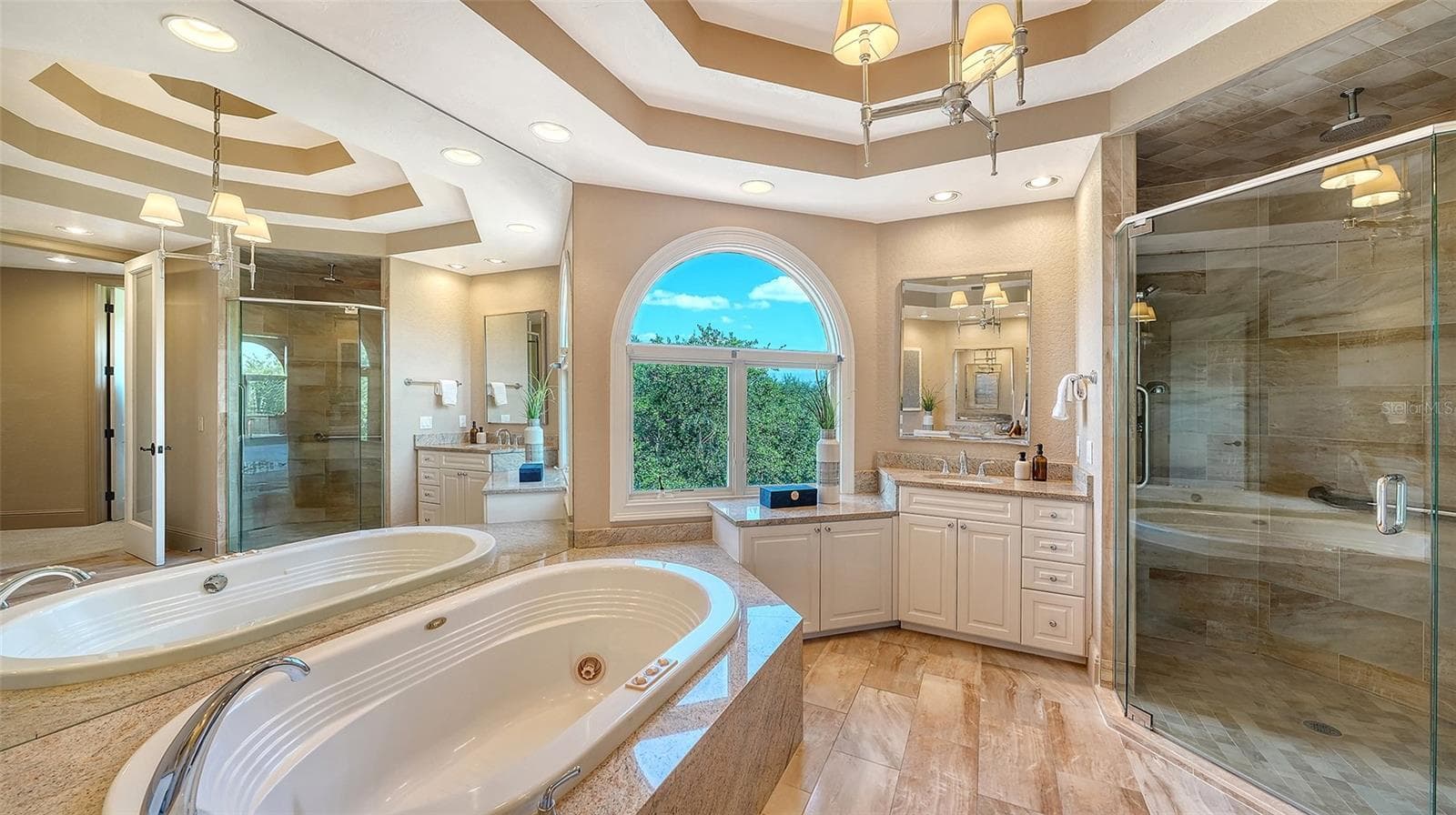 A spacious glass enclosed shower and soaking tub complement the beautifully appointed primary suite. - 168 COASTAL HAMMOCK CT, OSPREY