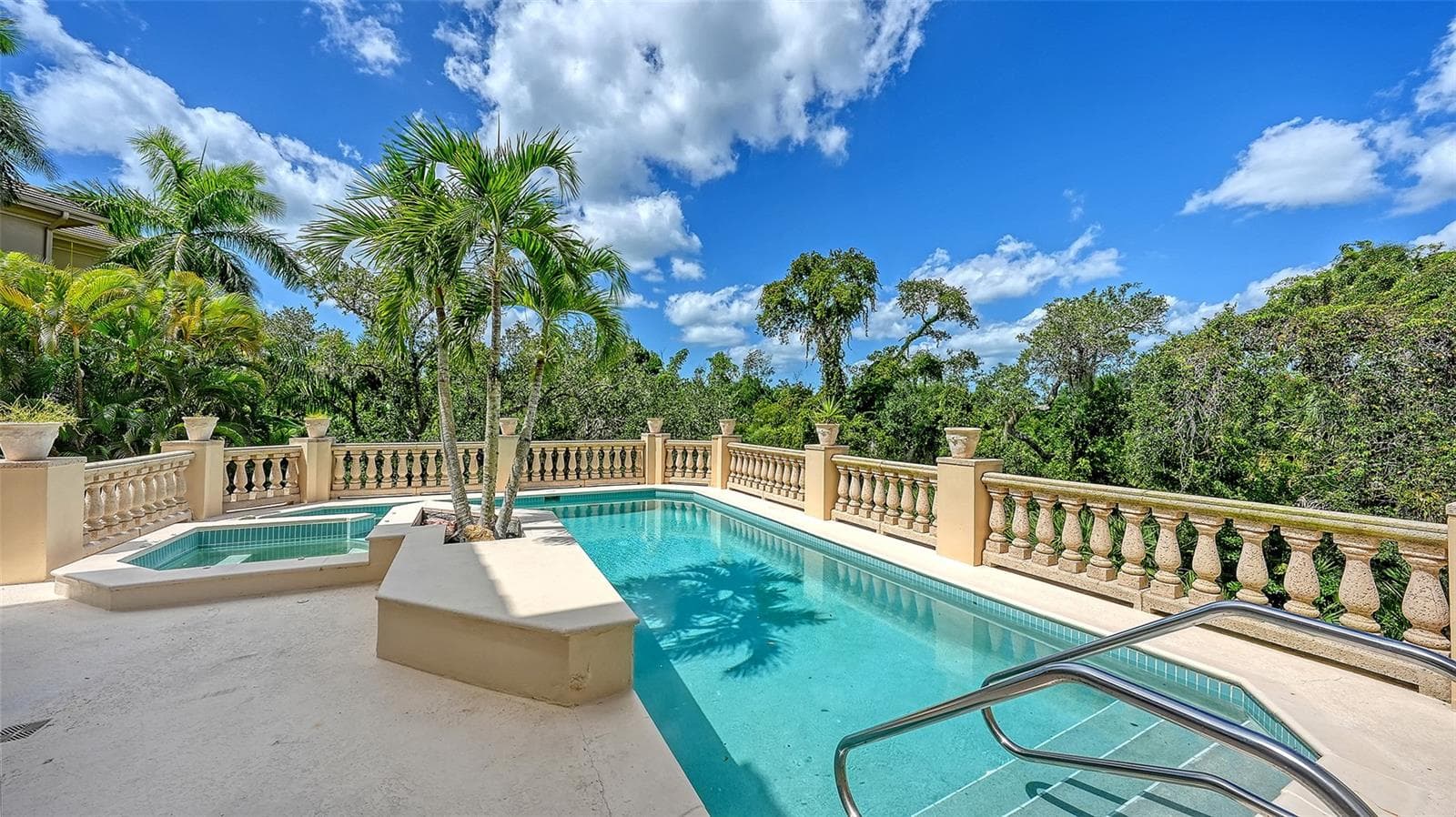 The elevated pool terrace is surrounded by tropical greenery, creating an intimate outdoor retreat. - 168 COASTAL HAMMOCK CT, OSPREY