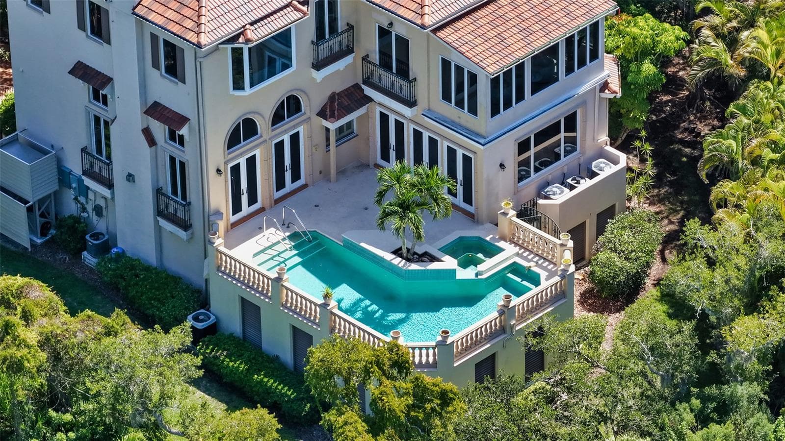 An aerial view highlights the home's elevated pool and spa tucked into the lush surrounding landscape. - 168 COASTAL HAMMOCK CT, OSPREY