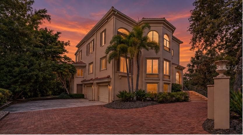 The home's distinctive architecture takes on a dramatic presence beneath Sarasota's colorful evening skies. - 168 COASTAL HAMMOCK CT, OSPREY