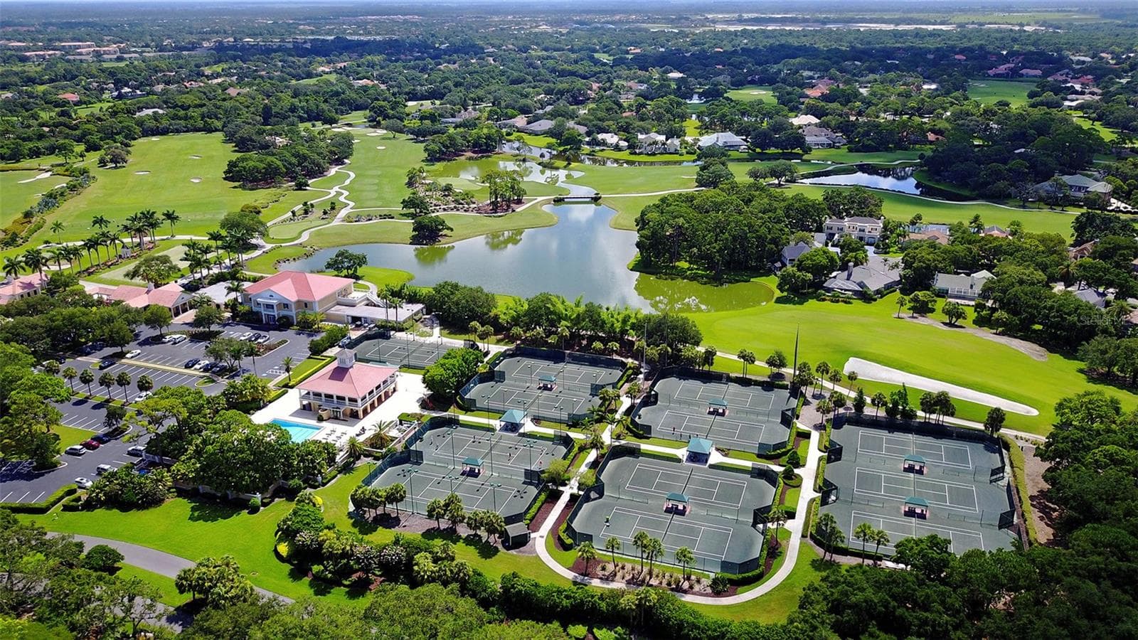 An aerial perspective highlights the expansive golf, lake and residential setting of this renowned private community. - 168 COASTAL HAMMOCK CT, OSPREY