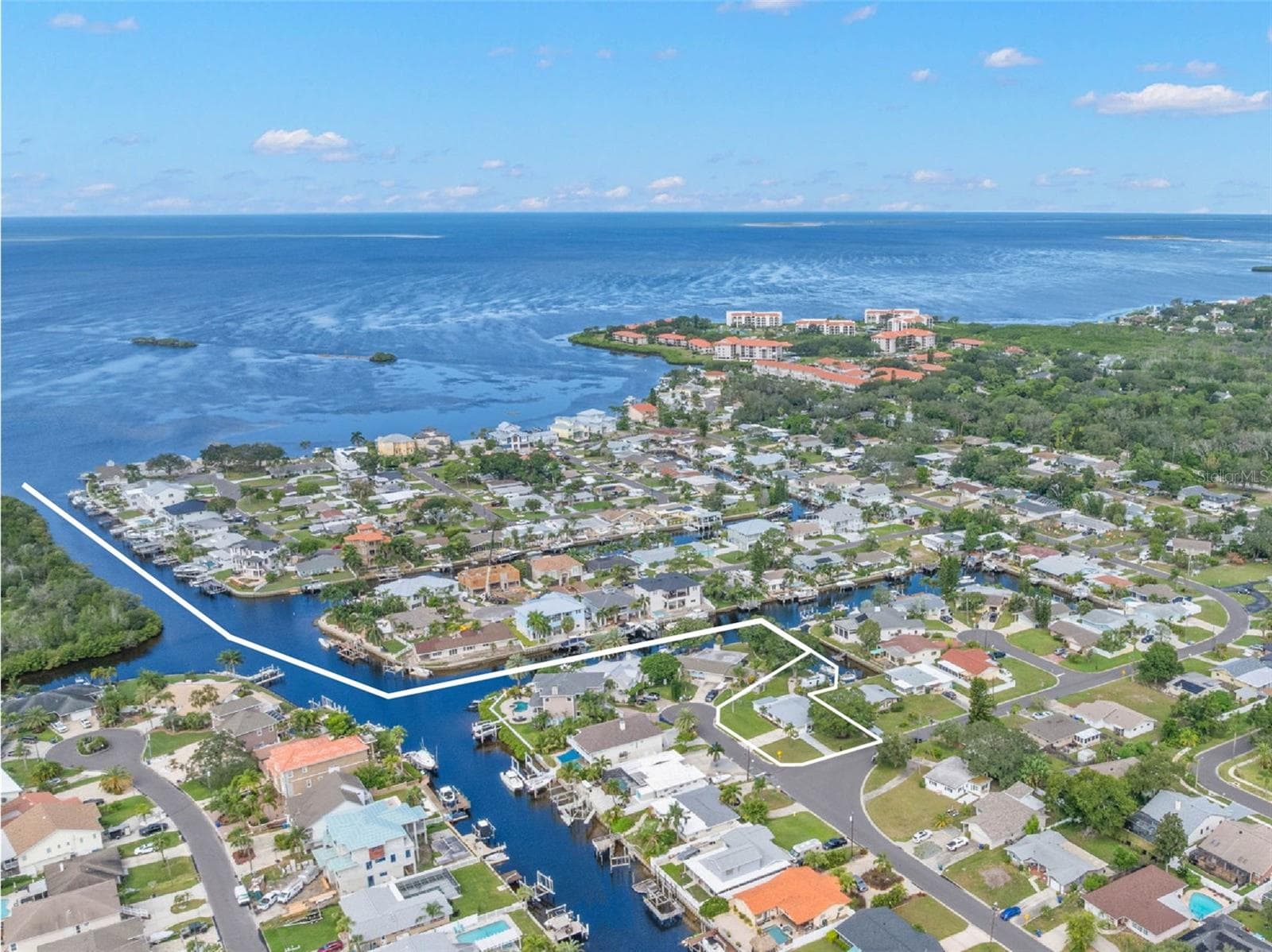A sweeping aerial view puts the waterfront setting in perspective, showing Baywood Village’s canal system winding toward the open Gulf of Mexico — a standout location for boaters who want direct saltwater access close to home. - 332 WESTWINDS DR, PALM HARBOR