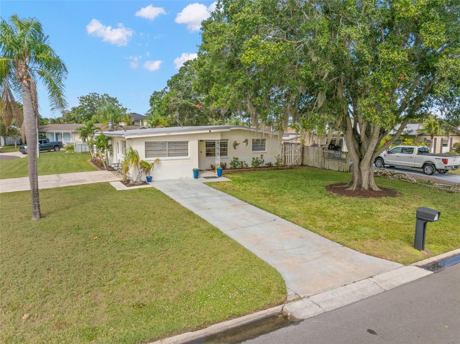 An elevated view highlights the home’s generous 11,800-square-foot corner setting, with a broad lawn, long driveway, mature shade trees, and the extra breathing room created by the one-and-a-half-lot property. - 332 WESTWINDS DR, PALM HARBOR
