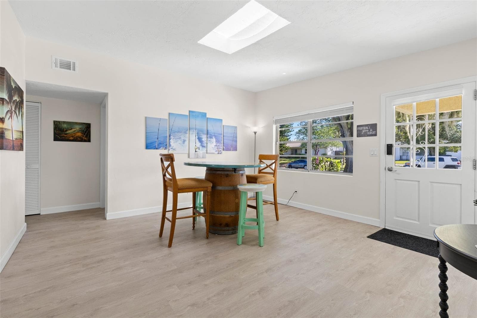 Step inside to a bright, open dining area with 2025 luxury vinyl plank flooring, a skylight overhead, and broad front windows that fill the space with natural light. - 332 WESTWINDS DR, PALM HARBOR