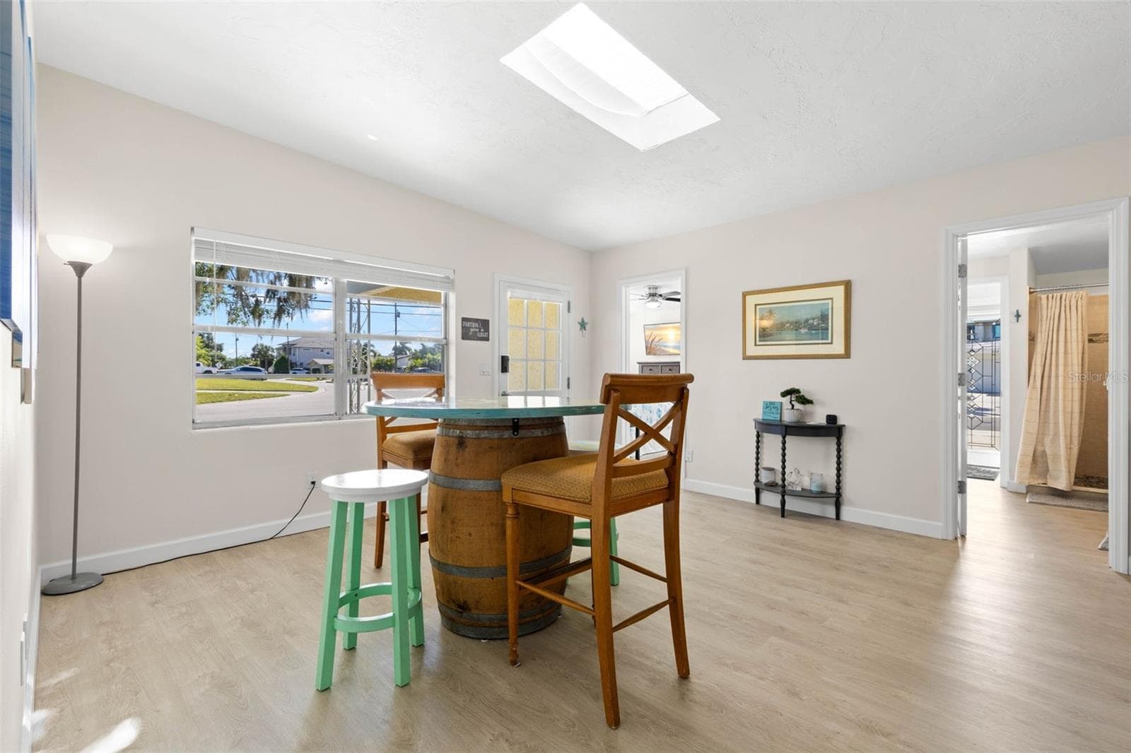 The bright dining area features 2025 luxury vinyl plank flooring, a skylight overhead, broad front windows, and plenty of room for everyday meals or entertaining. - 332 WESTWINDS DR, PALM HARBOR