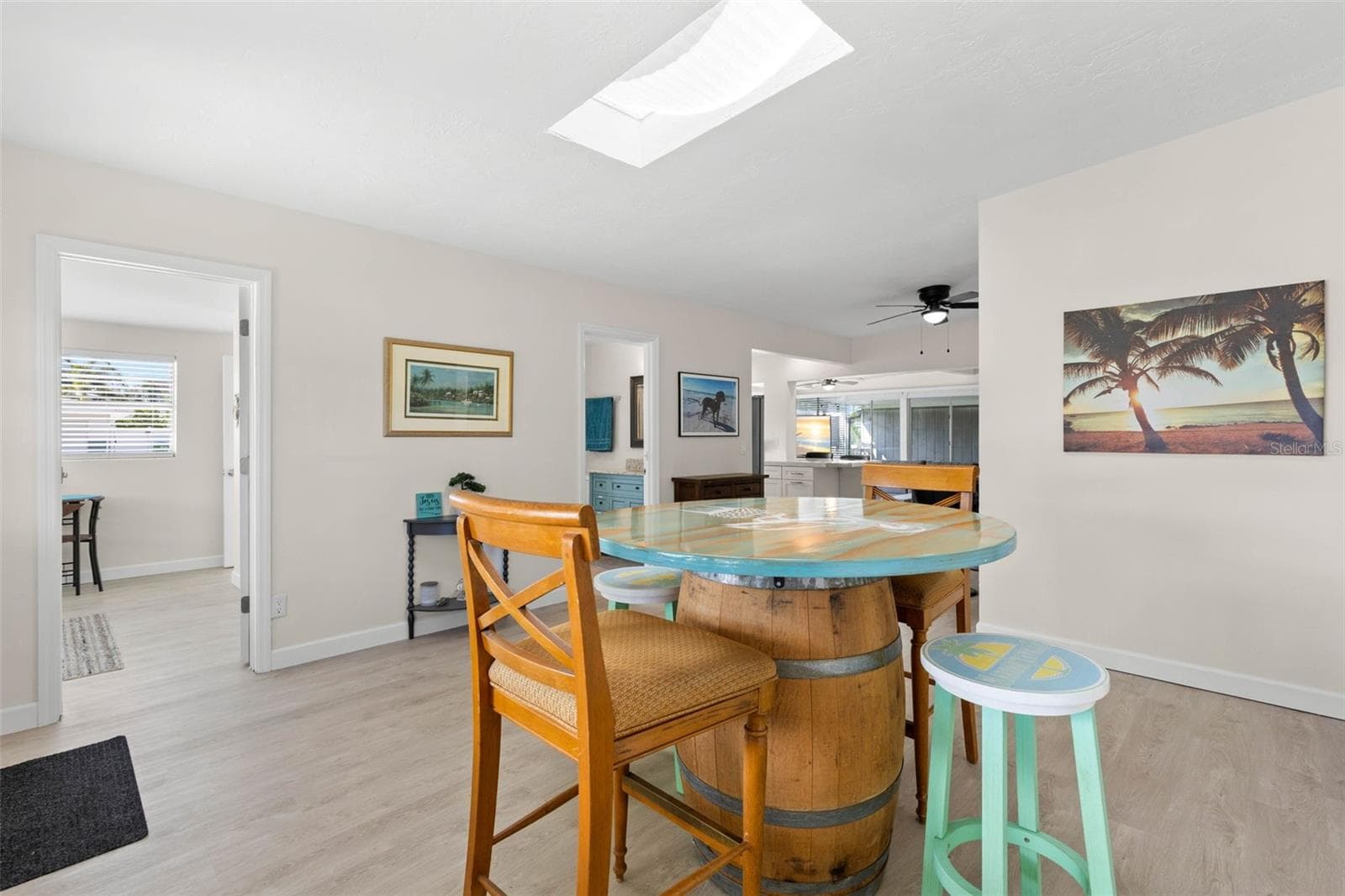 The spacious dining area is filled with natural light from the skylight and flows easily into the adjoining kitchen and living spaces, with 2025 luxury vinyl plank flooring creating a clean, cohesive look. - 332 WESTWINDS DR, PALM HARBOR