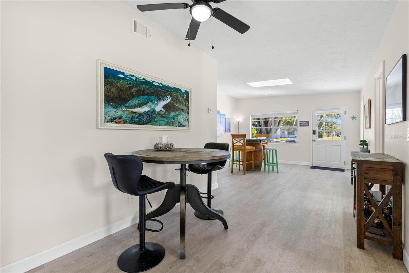 A flexible casual dining area features neutral tones, 2025 luxury vinyl plank flooring, and a ceiling fan, with an open layout that easily accommodates a breakfast table, work-from-home spot, or additional gathering space. - 332 WESTWINDS DR, PALM HARBOR