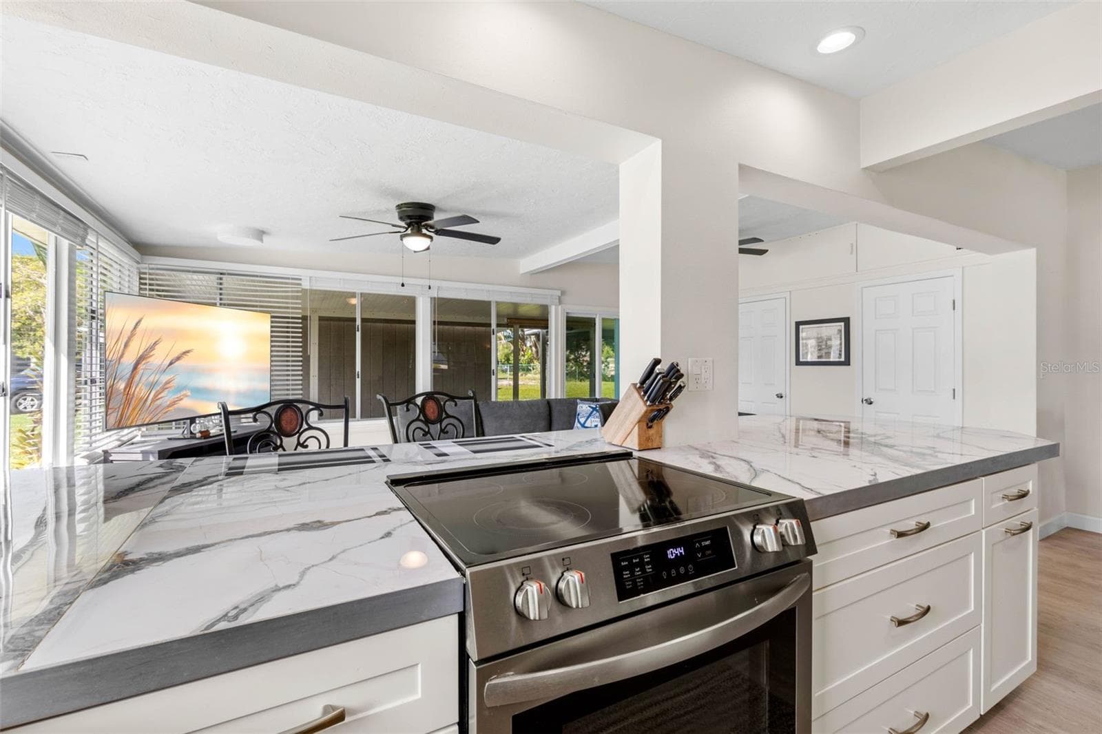 The updated kitchen (2025) showcases dramatic stone-look countertops, white Shaker-style cabinetry, stainless steel appliances, recessed lighting, and generous drawer storage, with an open design that keeps the cook connected to the adjoining living space. - 332 WESTWINDS DR, PALM HARBOR