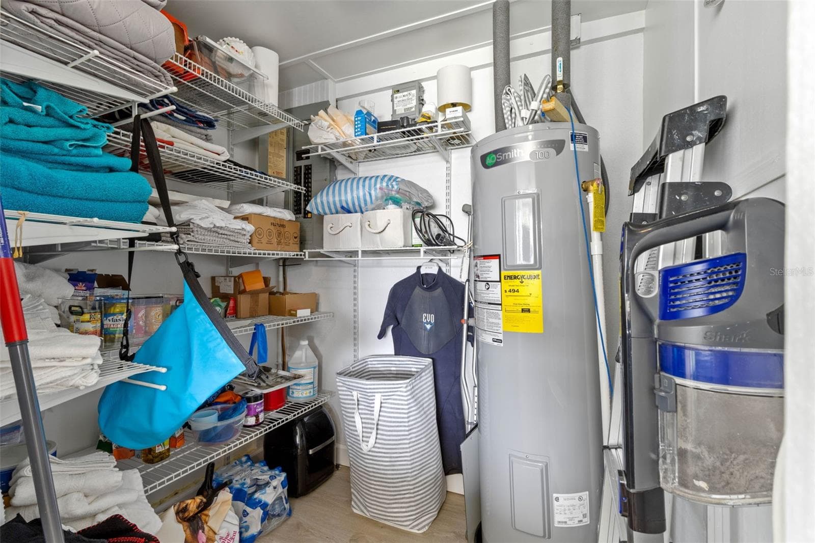 A dedicated utility and storage room keeps household essentials organized with extensive wire shelving and a water heater (2025) tucked neatly to one side. - 332 WESTWINDS DR, PALM HARBOR