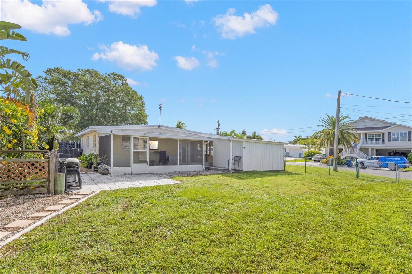 A spacious screened lanai extends across the rear of the home, offering plenty of covered space for relaxing, dining, and enjoying the backyard. - 332 WESTWINDS DR, PALM HARBOR
