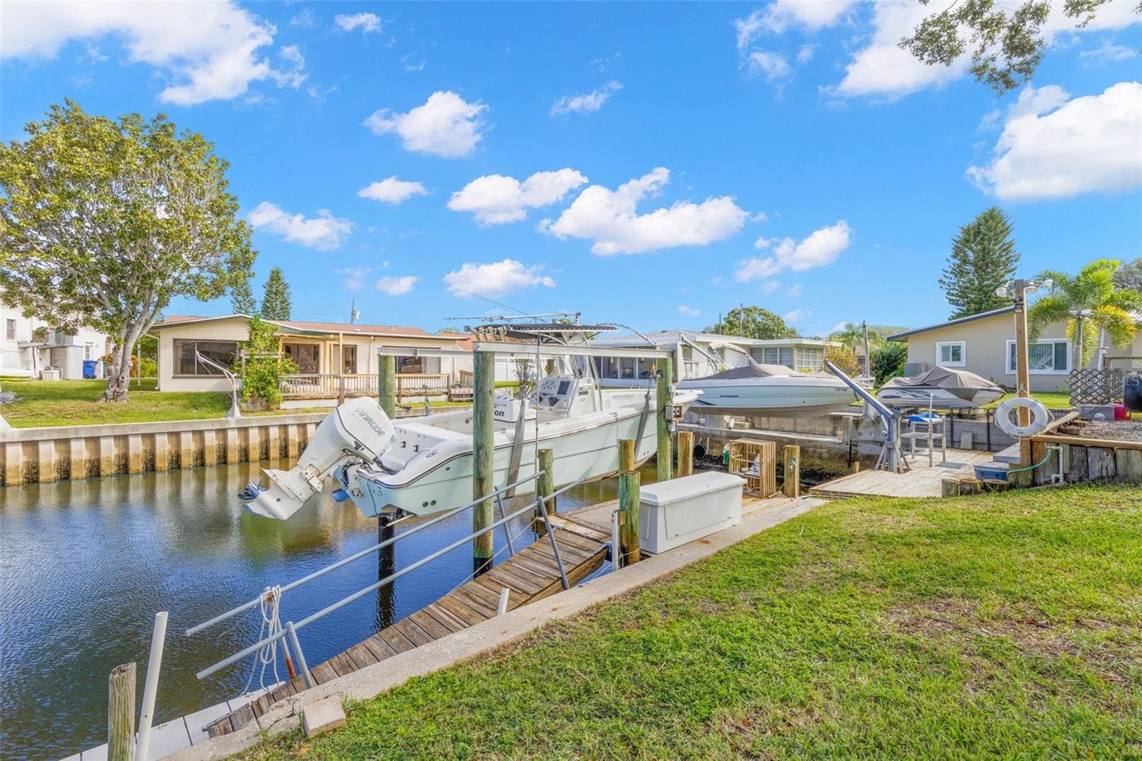 The canal frontage is equipped for easy days on the water, with a 10,000-pound boat lift, wooden dock, railed access walkway, waterside storage, and approximately 60 feet of seawall, all just steps from the backyard. - 332 WESTWINDS DR, PALM HARBOR