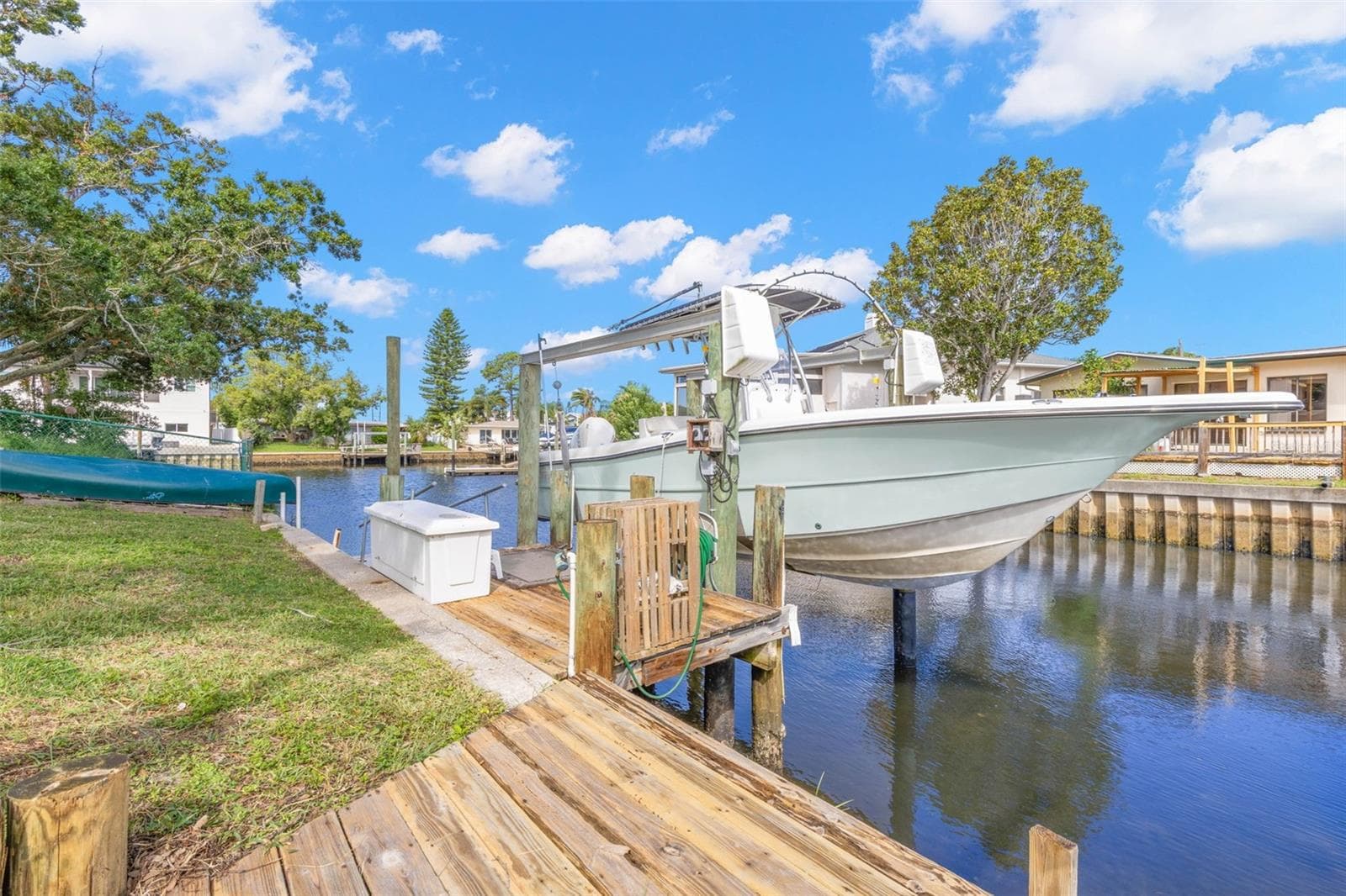 The waterfront setup is ready for serious boating, with a substantial wooden dock, 10,000-pound boat lift with davits, waterside storage, and a convenient water connection—all directly on the canal with access toward the Gulf. - 332 WESTWINDS DR, PALM HARBOR