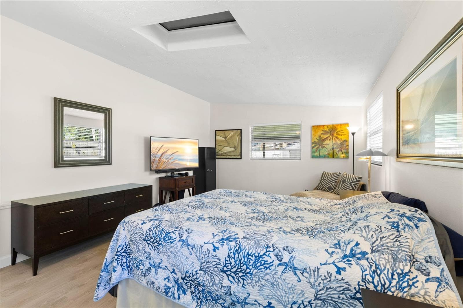 The primary bedroom offers exceptional space for both sleeping and lounging, with multiple windows, a skylight, neutral tones, and luxury vinyl plank flooring (2025) keeping the room bright and cohesive. - 332 WESTWINDS DR, PALM HARBOR
