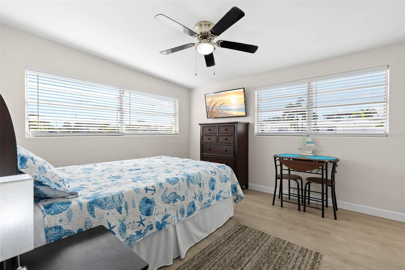 The third bedroom features two walls of windows, a ceiling fan, neutral tones, and luxury vinyl plank flooring (2025), with enough space for both sleeping and a small sitting or study area. - 332 WESTWINDS DR, PALM HARBOR