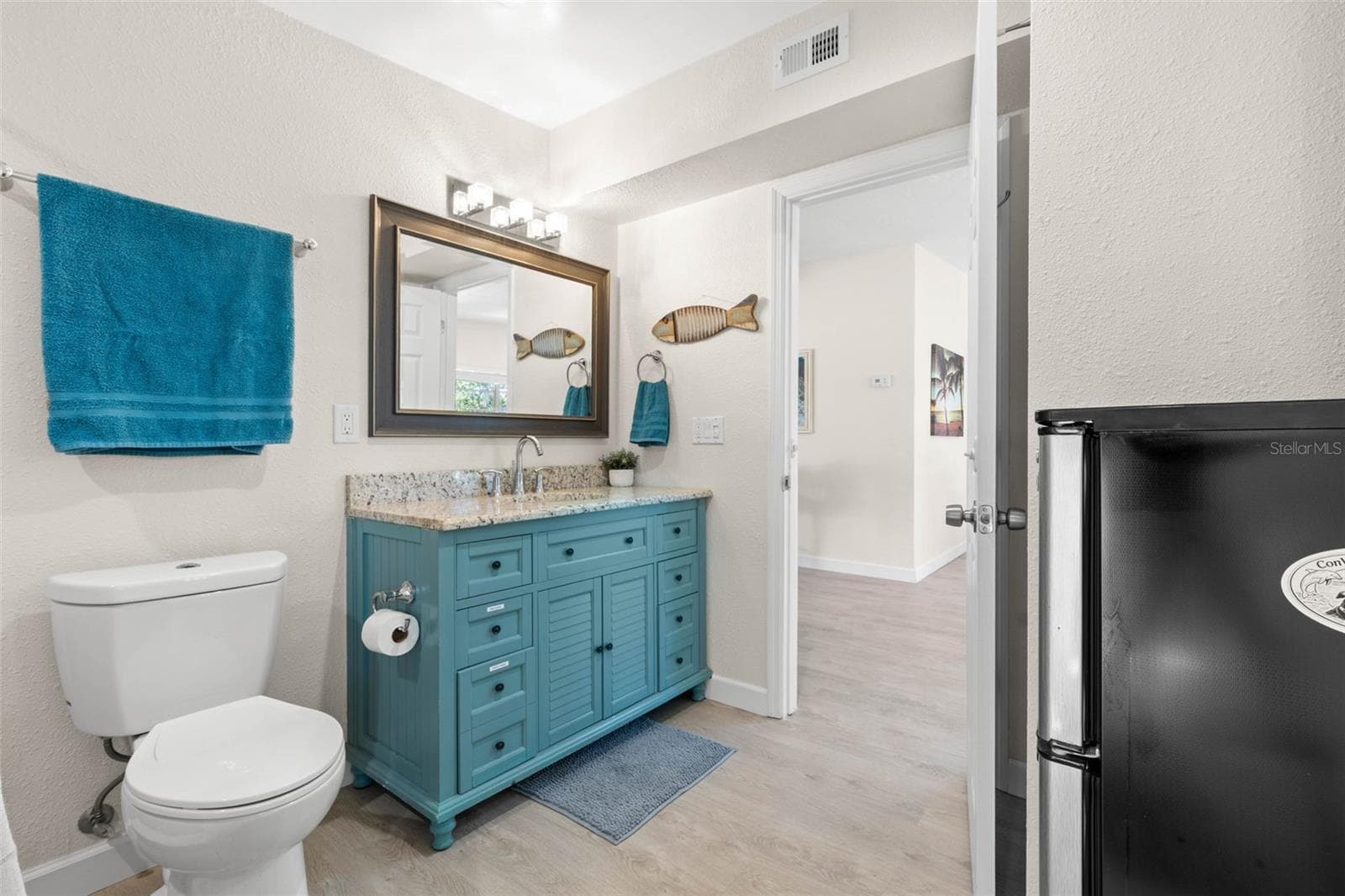 The updated second bath (2019) adds a splash of personality with a turquoise vanity, stone-look countertop, framed mirror, modern lighting, and plenty of built-in storage. - 332 WESTWINDS DR, PALM HARBOR