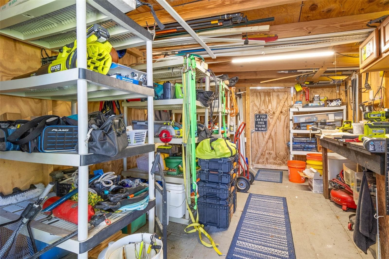 A dedicated workshop offers serious utility with abundant shelving, a long workbench, overhead storage, lighting, and plenty of room for tools, fishing gear, projects, and everyday equipment. - 332 WESTWINDS DR, PALM HARBOR