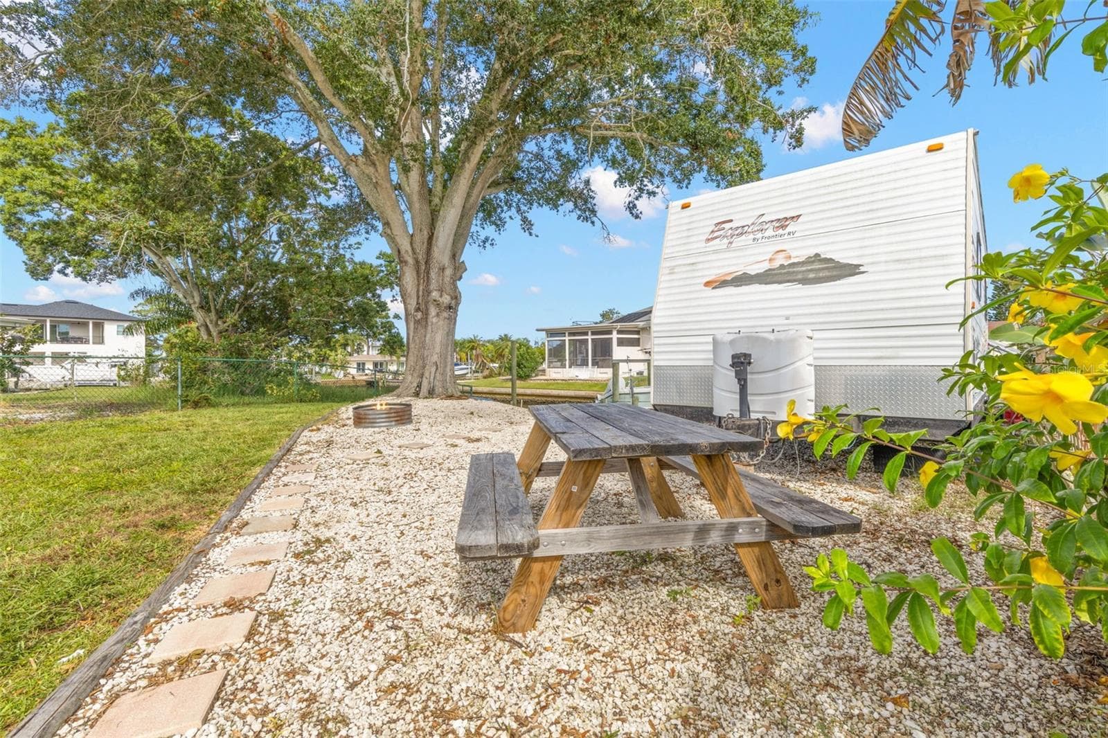 The oversized side yard offers dedicated space for RV, boat, or trailer parking, along with a gravel picnic area beneath a mature shade tree—another benefit of this generous 11,800-square-foot property. - 332 WESTWINDS DR, PALM HARBOR