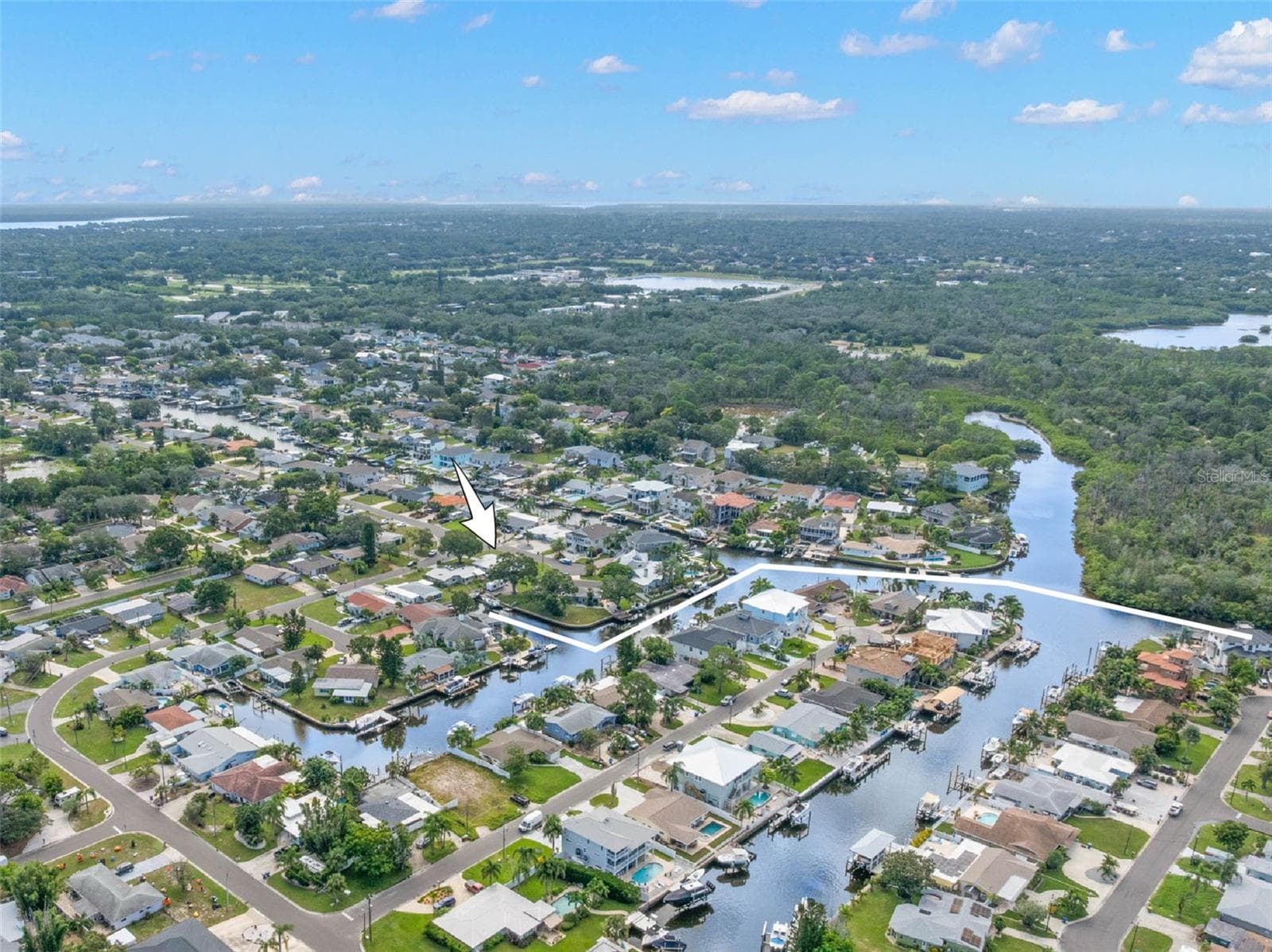 An aerial view showcases Baywood Village’s network of saltwater canals and the home’s close-to-the-water setting, with direct Gulf access from the neighborhood and easy reach of Tarpon Springs, Fred Howard Park, Sunset Beach, and Wall Springs Park. - 332 WESTWINDS DR, PALM HARBOR