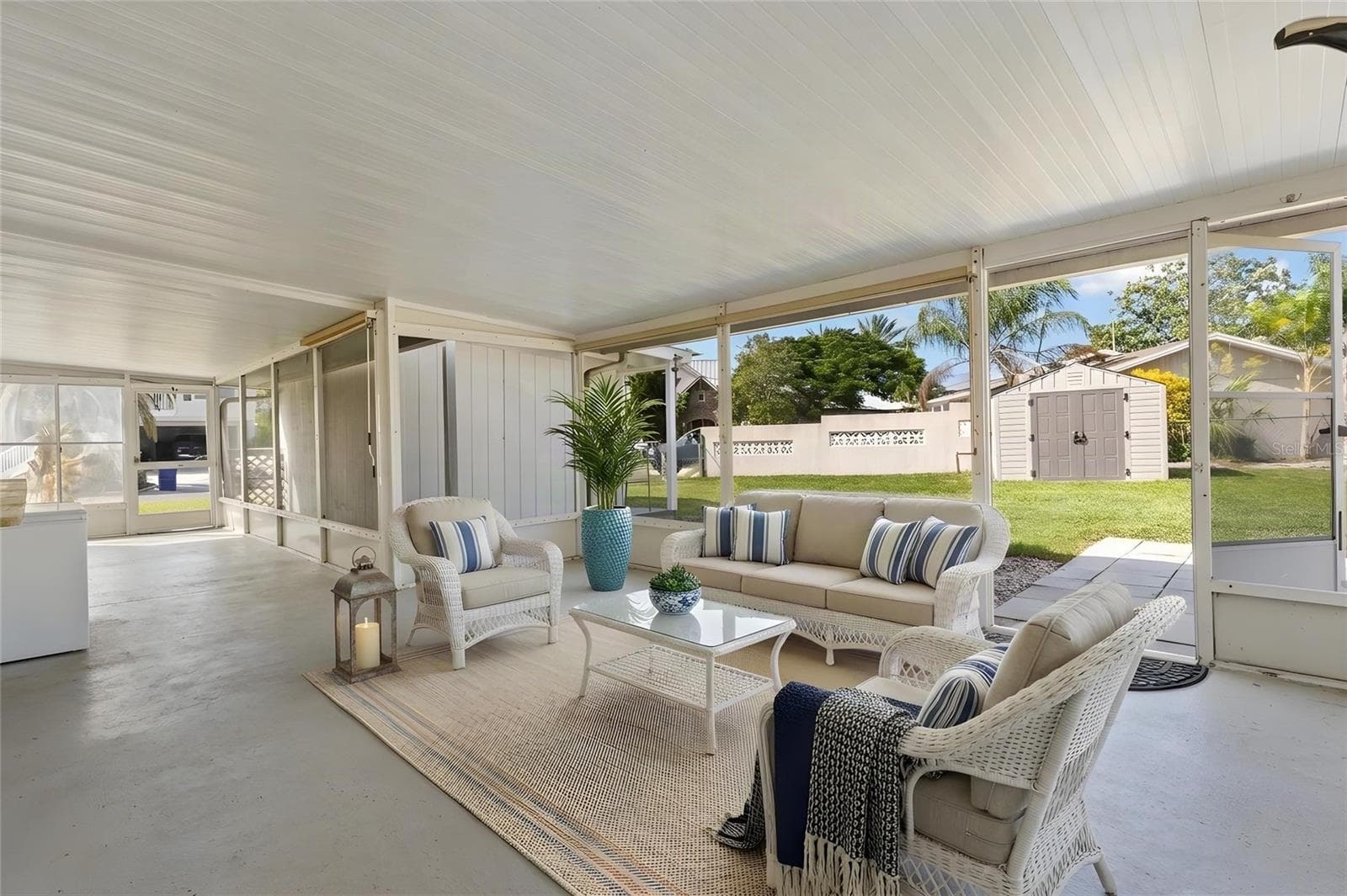 The screened lanai opens directly to the backyard, creating a generous covered space for dining, lounging, or entertaining, with easy access to the lawn and outdoor storage shed. - 332 WESTWINDS DR, PALM HARBOR