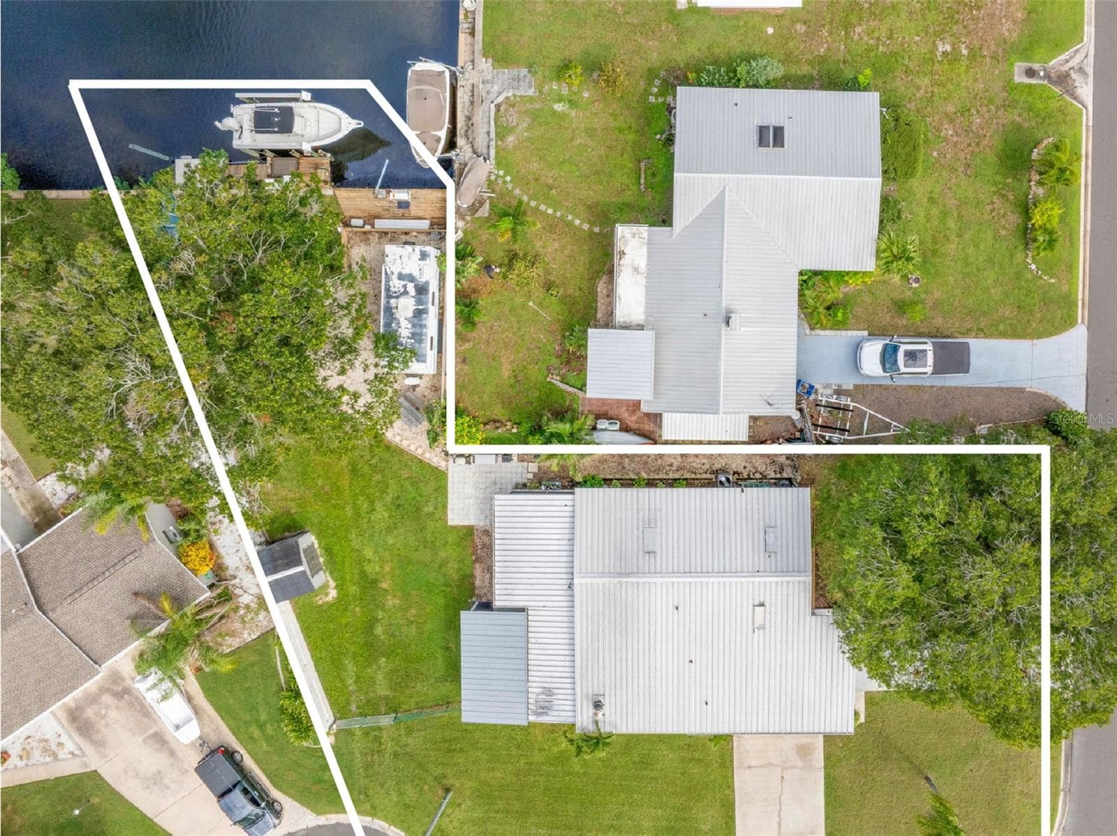 A straight-down aerial view highlights the property from street to canal, showing the generous yard, long driveway, screened lanai, RV parking area, and private waterfront setup all in one frame. - 332 WESTWINDS DR, PALM HARBOR