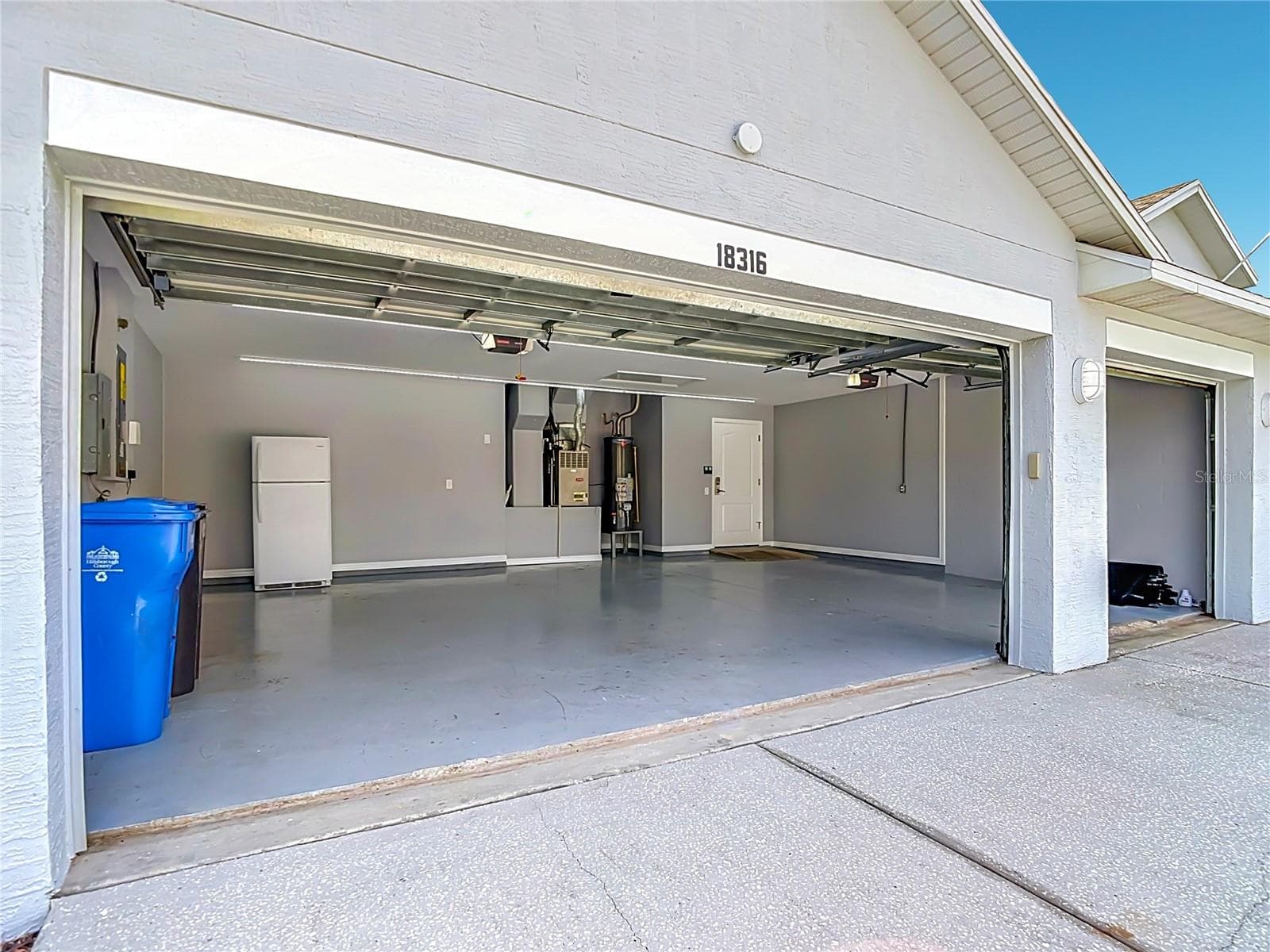 The impressive 3 car garage offers exceptional versatility and functionality, featuring a dedicated electrical panel ideal for a workshop or electric vehicle charging, along with high-output LED shop lighting - 18316 CYPRESS HAVEN DR, TAMPA