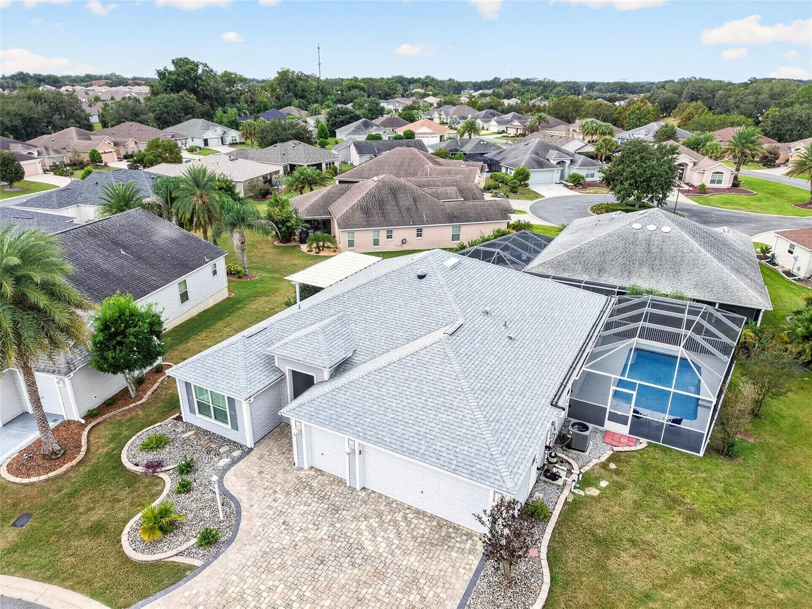 This aerial view showcases the screened pool retreat, pergola patio, and beautifully landscaped grounds, offering inviting spaces to relax and entertain. - 2454 MORNING DOVE LN, THE VILLAGES