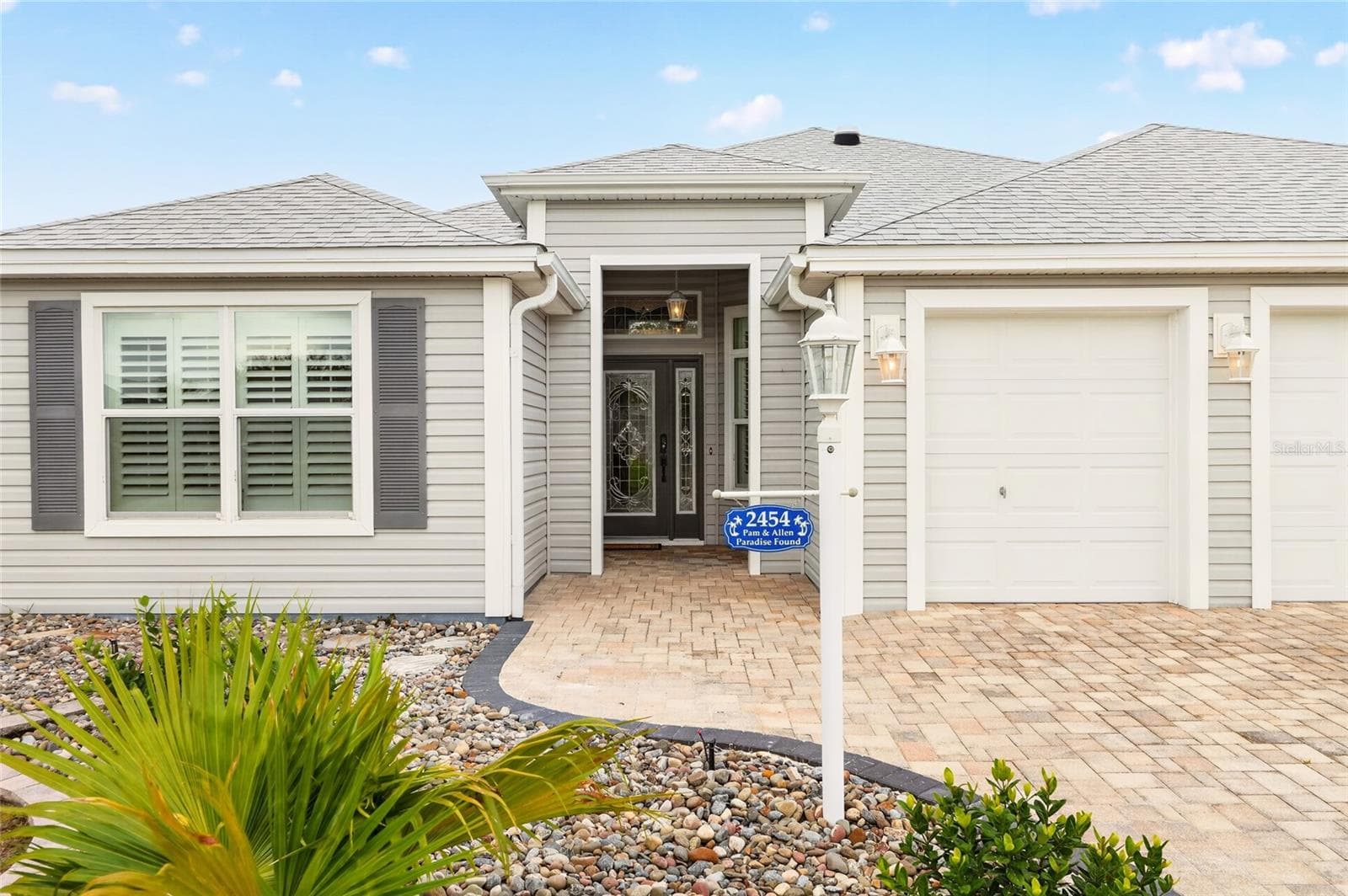 Beautiful landscaping, a paver driveway, and a welcoming covered entry create inviting curb appeal for this charming Florida home. - 2454 MORNING DOVE LN, THE VILLAGES
