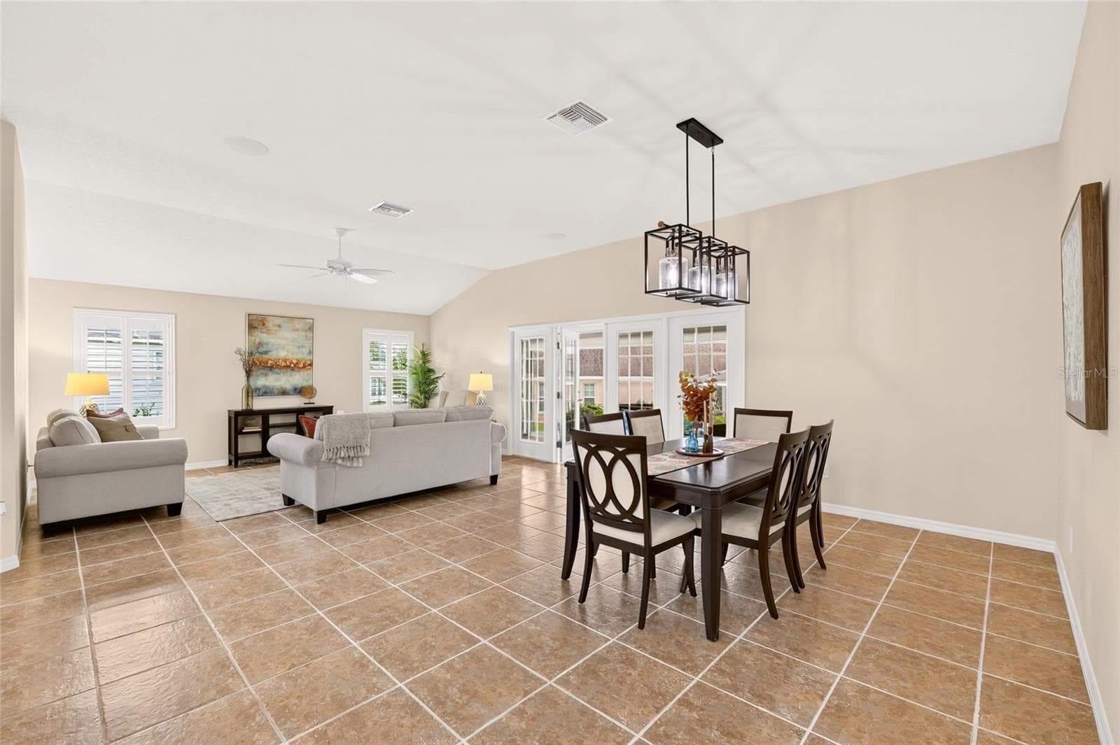 VOLUME CEILINGS, beautiful TILE FLOORING, and PLANTATION SHUTTERS enhance the open living and dining area, with French doors leading to the enclosed lanai for effortless entertaining. - 2454 MORNING DOVE LN, THE VILLAGES