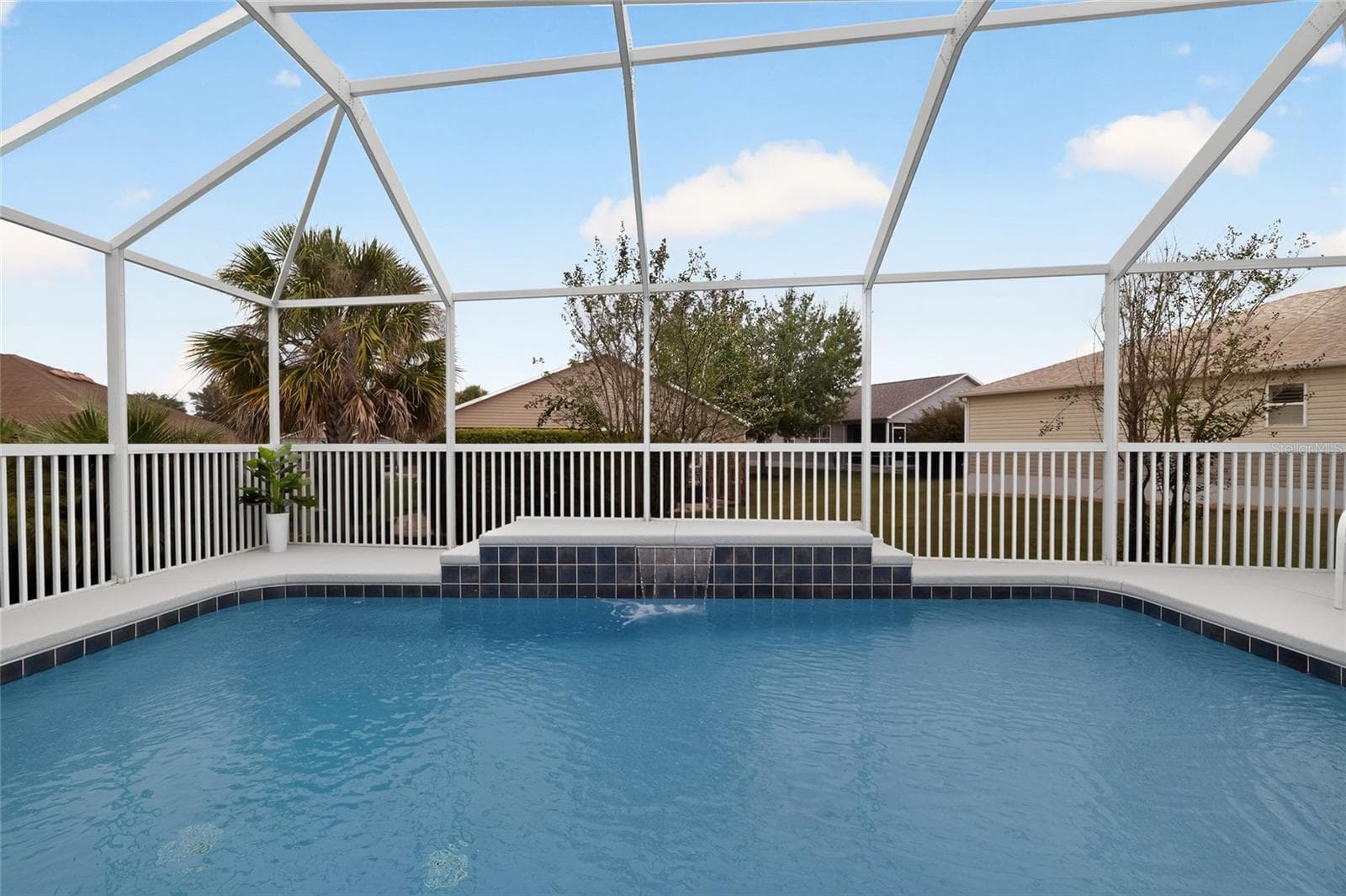 Enjoy a refreshing dip in the sparkling pool while the soothing waterfall creates a relaxing retreat beneath the spacious screened birdcage. - 2454 MORNING DOVE LN, THE VILLAGES