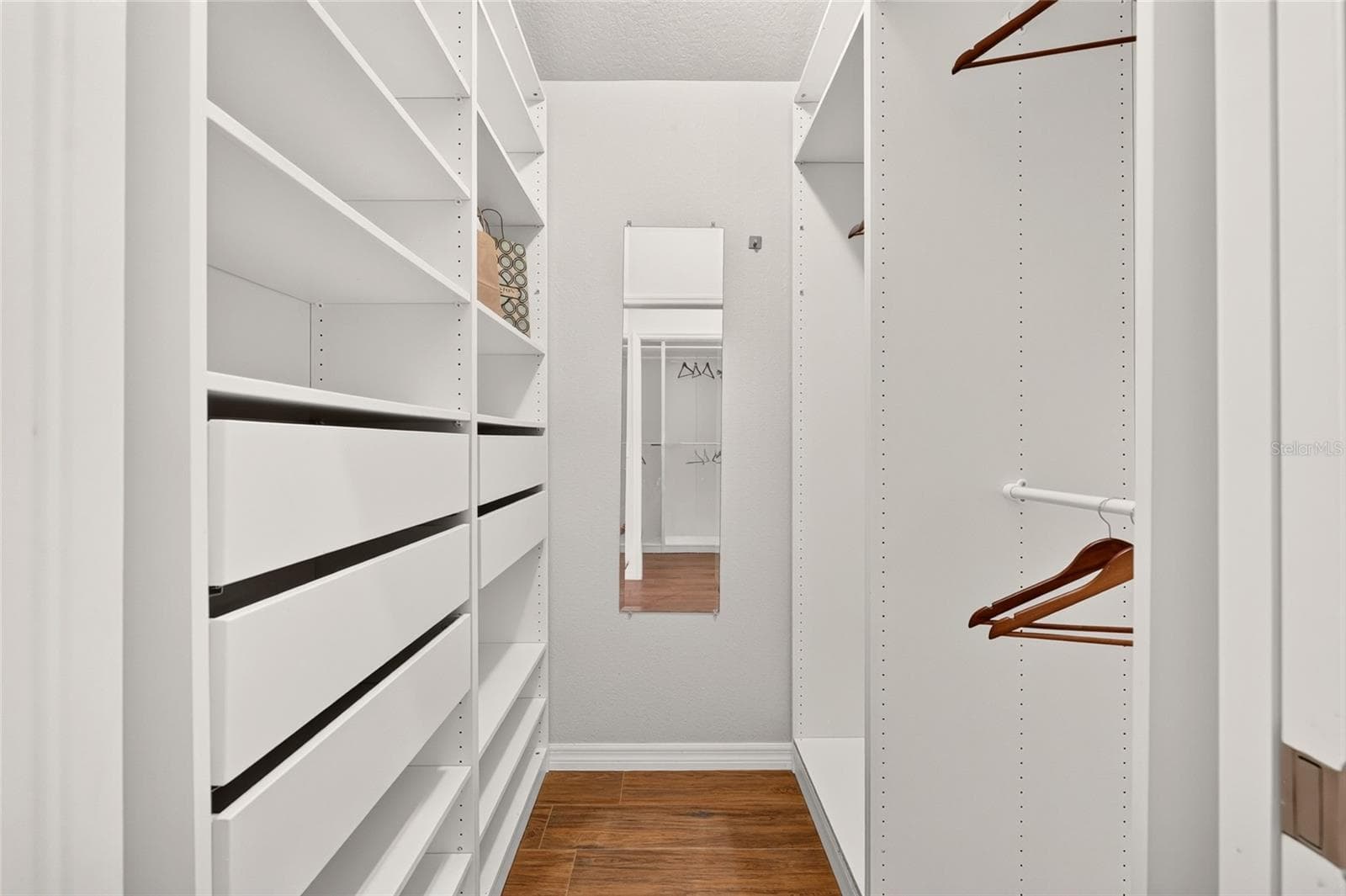 A beautifully organized CUSTOM WALK-IN CLOSET features adjustable shelving, multiple hanging rods, and pull-out baskets to keep clothing and accessories neatly within reach. - 2454 MORNING DOVE LN, THE VILLAGES