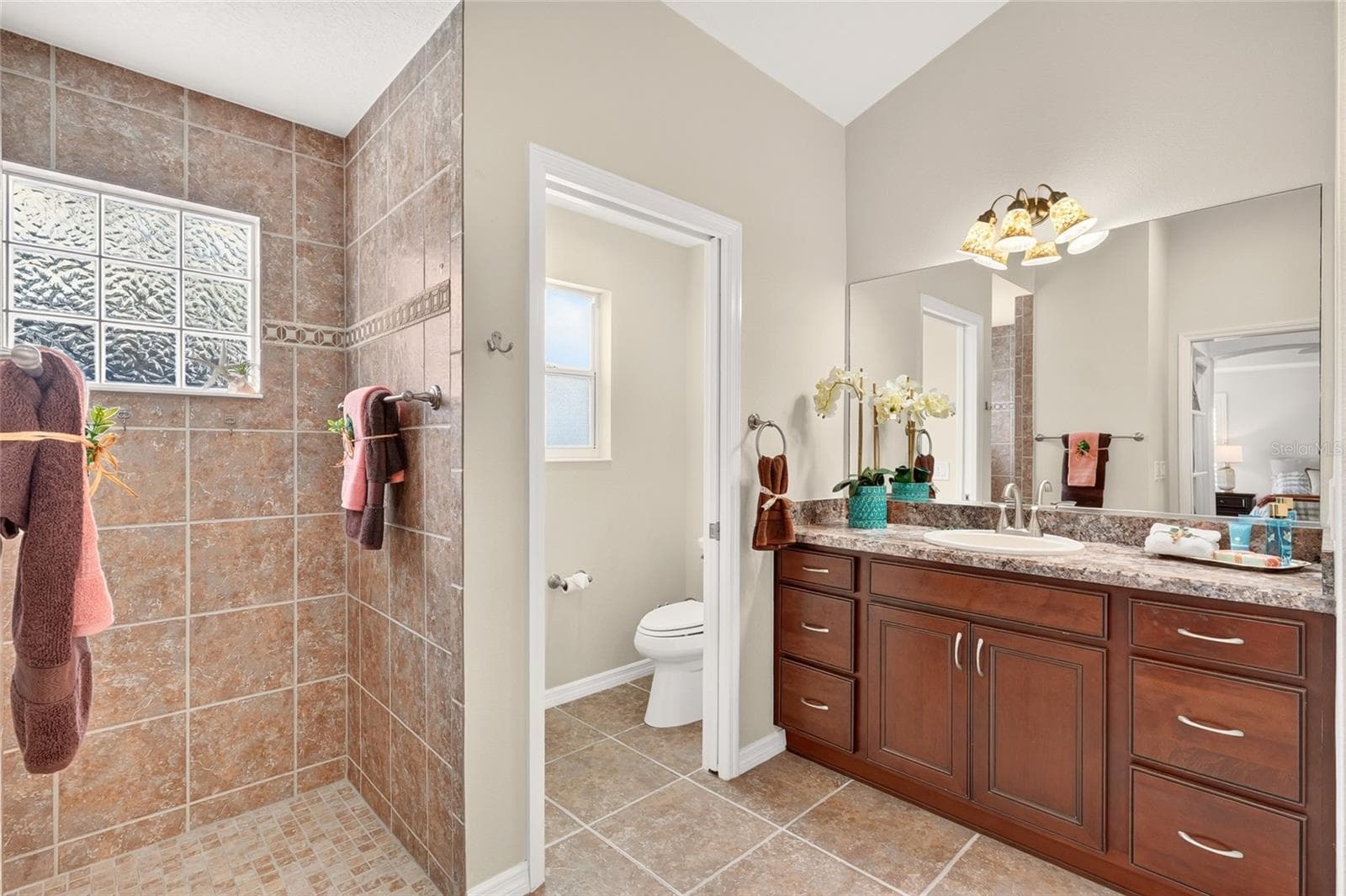 The PRIMARY BATH offers DUAL VANITIES, generous cabinet storage, and a spacious tiled ROMAN SHOWER for a relaxing start to your day! - 2454 MORNING DOVE LN, THE VILLAGES