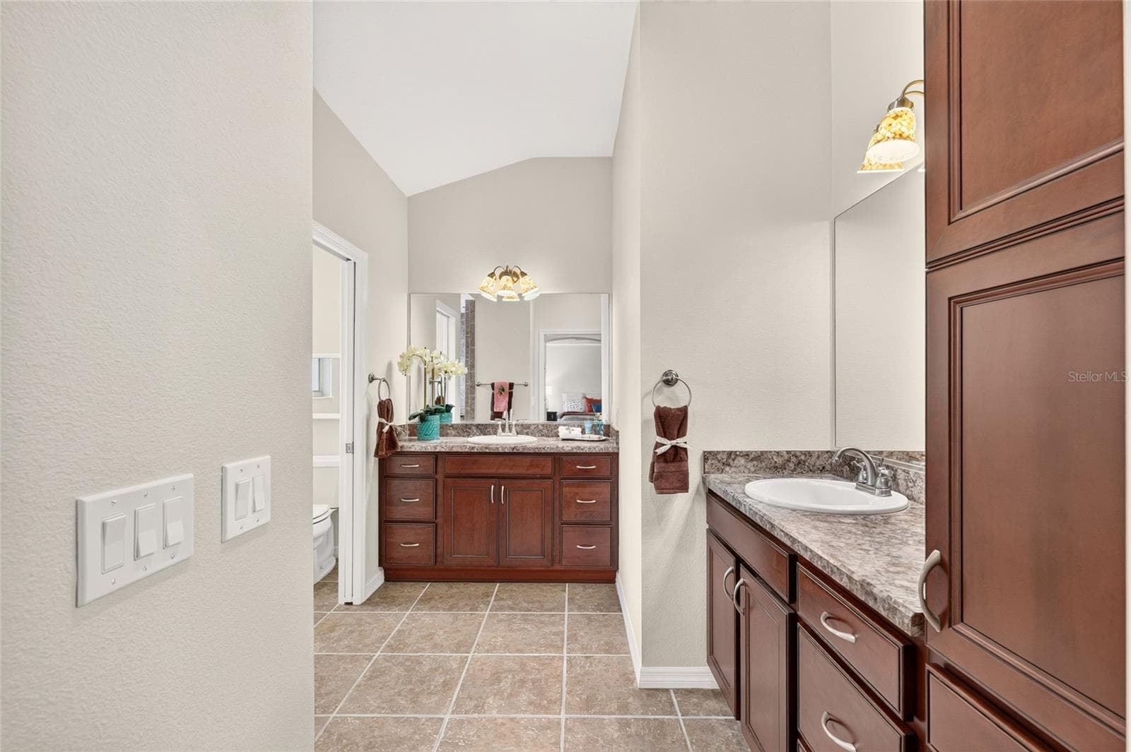The spacious PRIMARY BATH combines DUAL VANITIES, rich cabinetry, and a tiled ROMAN SHOWER, with a separate water closet for added privacy. - 2454 MORNING DOVE LN, THE VILLAGES