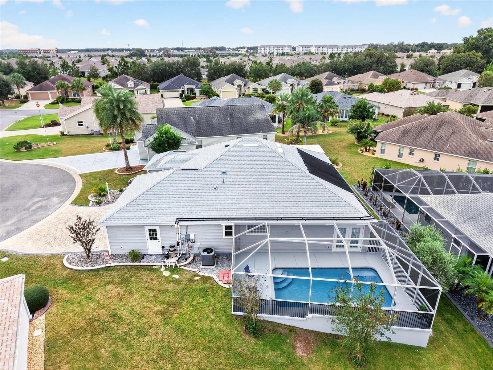 This aerial view showcases the SCREENED POOL RETREAT, SOLAR POOL HEATING PANELS, and spacious backyard—offering plenty of room to enjoy the Florida sunshine! - 2454 MORNING DOVE LN, THE VILLAGES