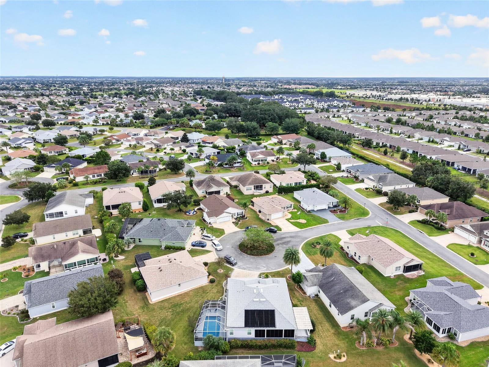 This elevated view from the rear showcases the SCREENED POOL RETREAT and spacious backyard, framed by a sweeping panorama of the surrounding neighborhood. - 2454 MORNING DOVE LN, THE VILLAGES