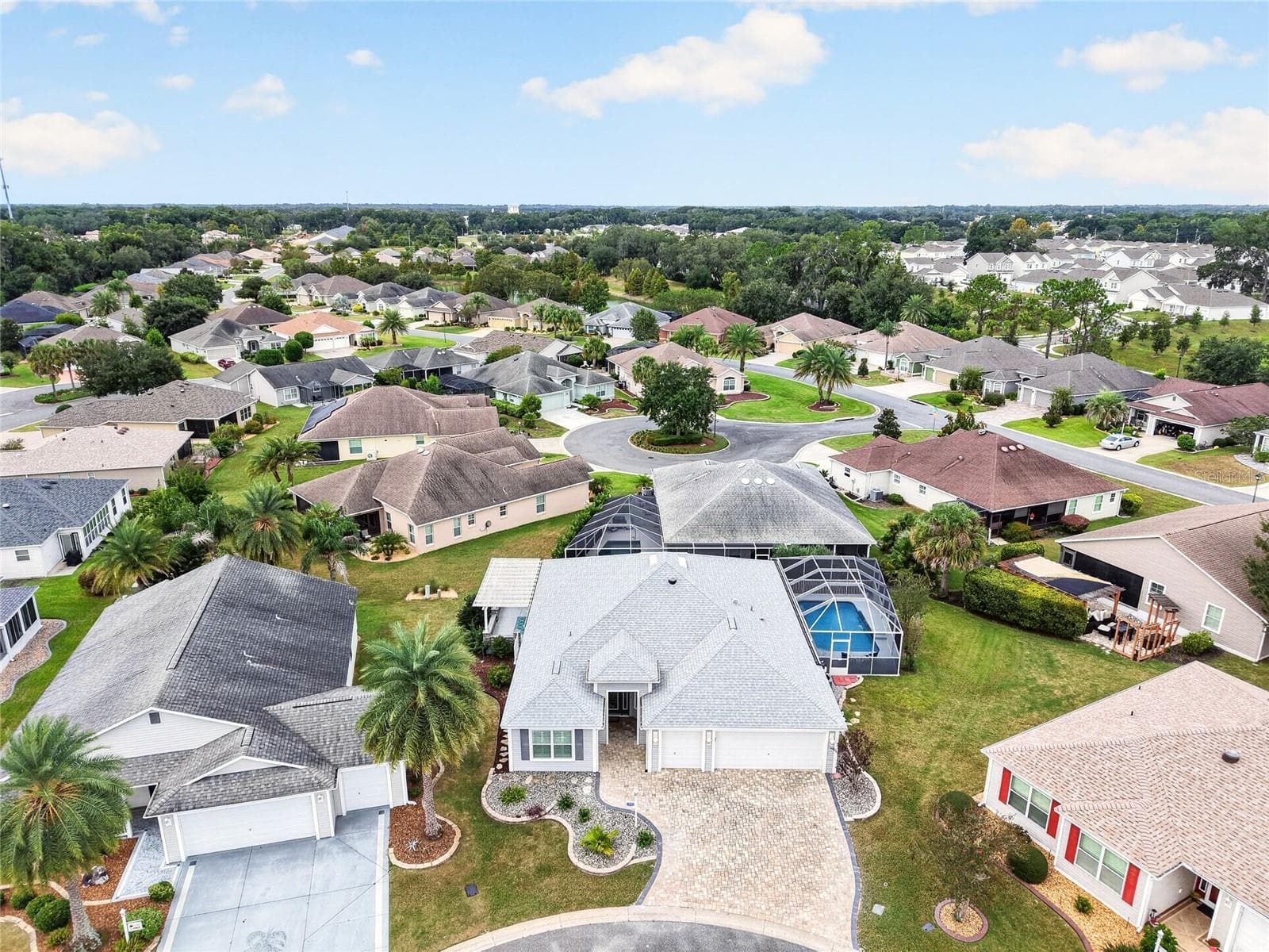 A bird’s-eye view captures this inviting home’s SCREENED POOL and surrounding neighborhood, with palm-lined streets setting the scene for THE VILLAGES LIFESTYLE! - 2454 MORNING DOVE LN, THE VILLAGES