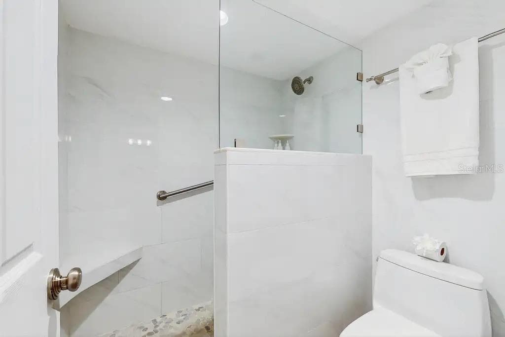 LARGE WALK-IN SHOWER OFF THE PRIMARY SUITE FEATURES A BUILT IN  BENCH FOR ADDED COMFORT AND RELAXATION. - 18400 GULF BLVD #1208, INDIAN SHORES