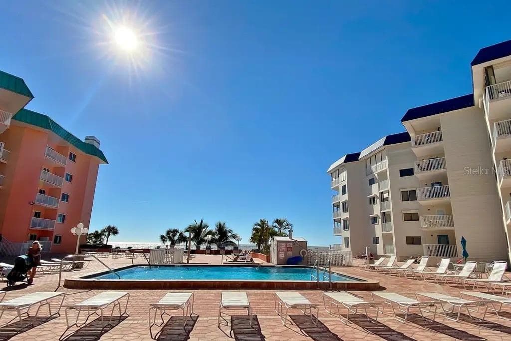 RESORT-STYLE POOL DECK COMPLETE WITH LOUNGE CHAIRS, TABLES AND UMBRELLAS FOR GUEST USE AND RELAXATION - 18400 GULF BLVD #1208, INDIAN SHORES