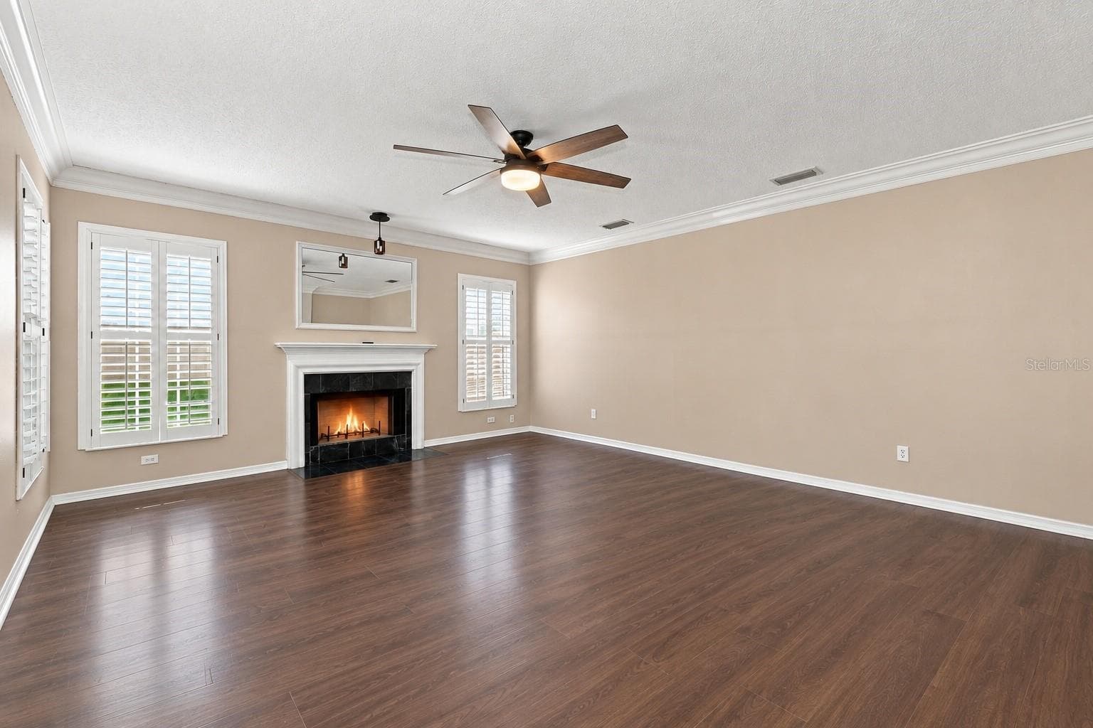 Spacious Formal Living Room featuring BRAND NEW LVP flooring, crown molding, plantation shutters, and a cozy wood-burning fireplace. - 1349 VALLEY PINE CIR, APOPKA