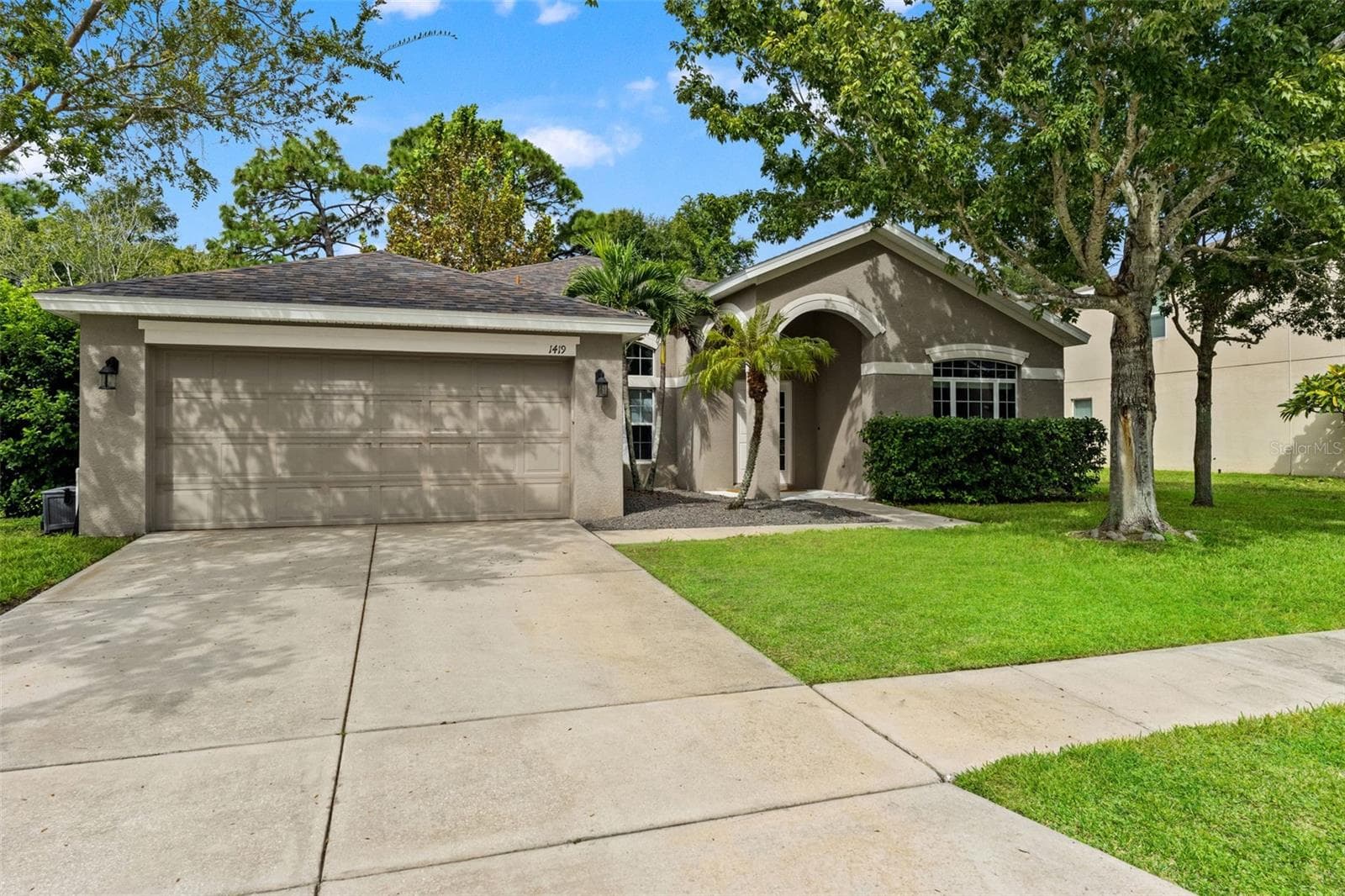 An extended driveway and two-car garage provide plenty of everyday parking and storage convenience. - 1419 BLUE MARLIN BLVD, HOLIDAY