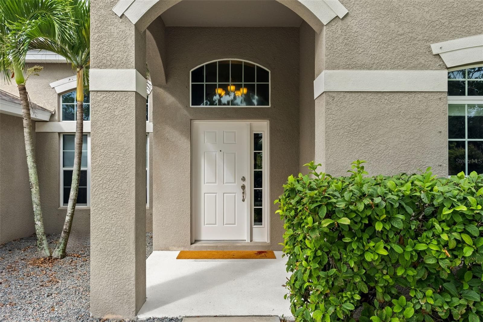 The covered front entry creates a welcoming arrival, with an arched transom bringing additional natural light inside. - 1419 BLUE MARLIN BLVD, HOLIDAY