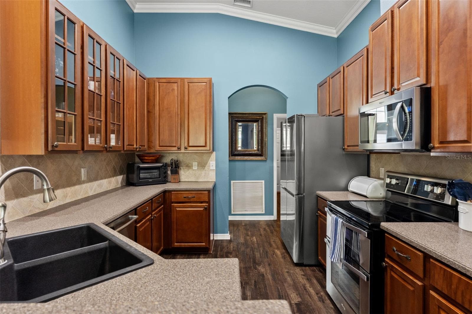 The kitchen offers abundant wood cabinetry, generous counter space, stainless appliances, and plenty of room for everyday meal prep. - 1419 BLUE MARLIN BLVD, HOLIDAY