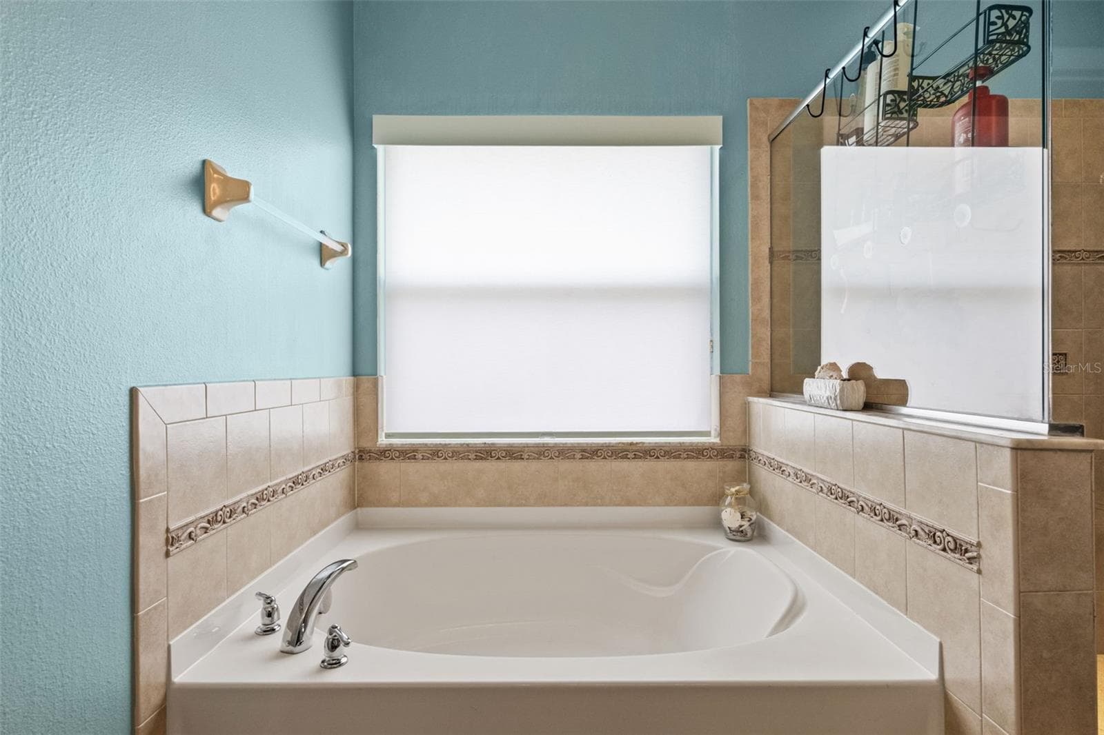 Unwind in the primary bath’s soaking tub, positioned beneath a large window for a bright, relaxing feel. - 1419 BLUE MARLIN BLVD, HOLIDAY