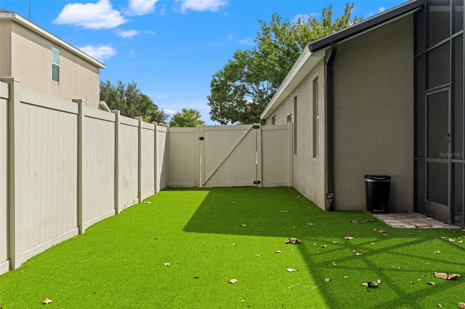 More pet-safe turf continues along the side of the home, maximizing usable fenced space while keeping yard maintenance simple. - 1419 BLUE MARLIN BLVD, HOLIDAY