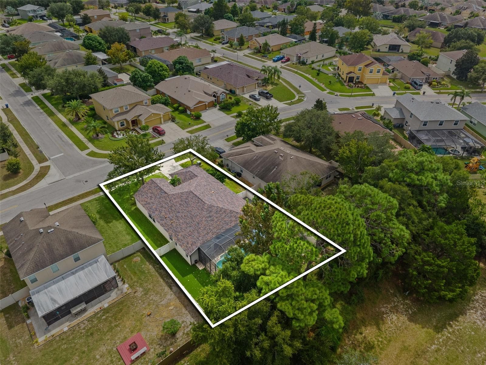 The aerial perspective really tells the story: a generous homesite, screened pool, fenced yard, and wooded privacy with no rear neighbors. - 1419 BLUE MARLIN BLVD, HOLIDAY